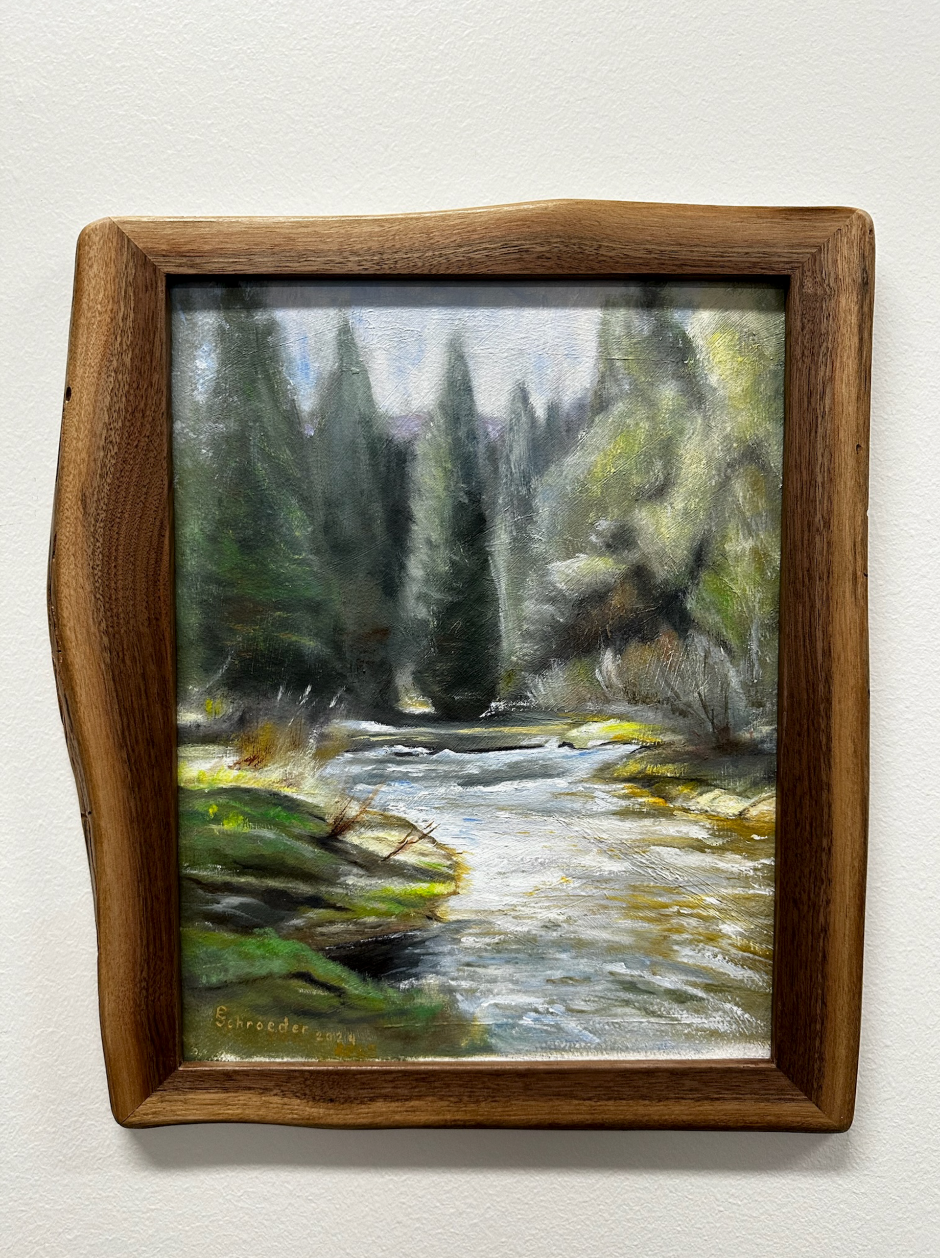 Oil painting of a river scene with trees, in a rustic wood frame. Green and blue hues dominate.