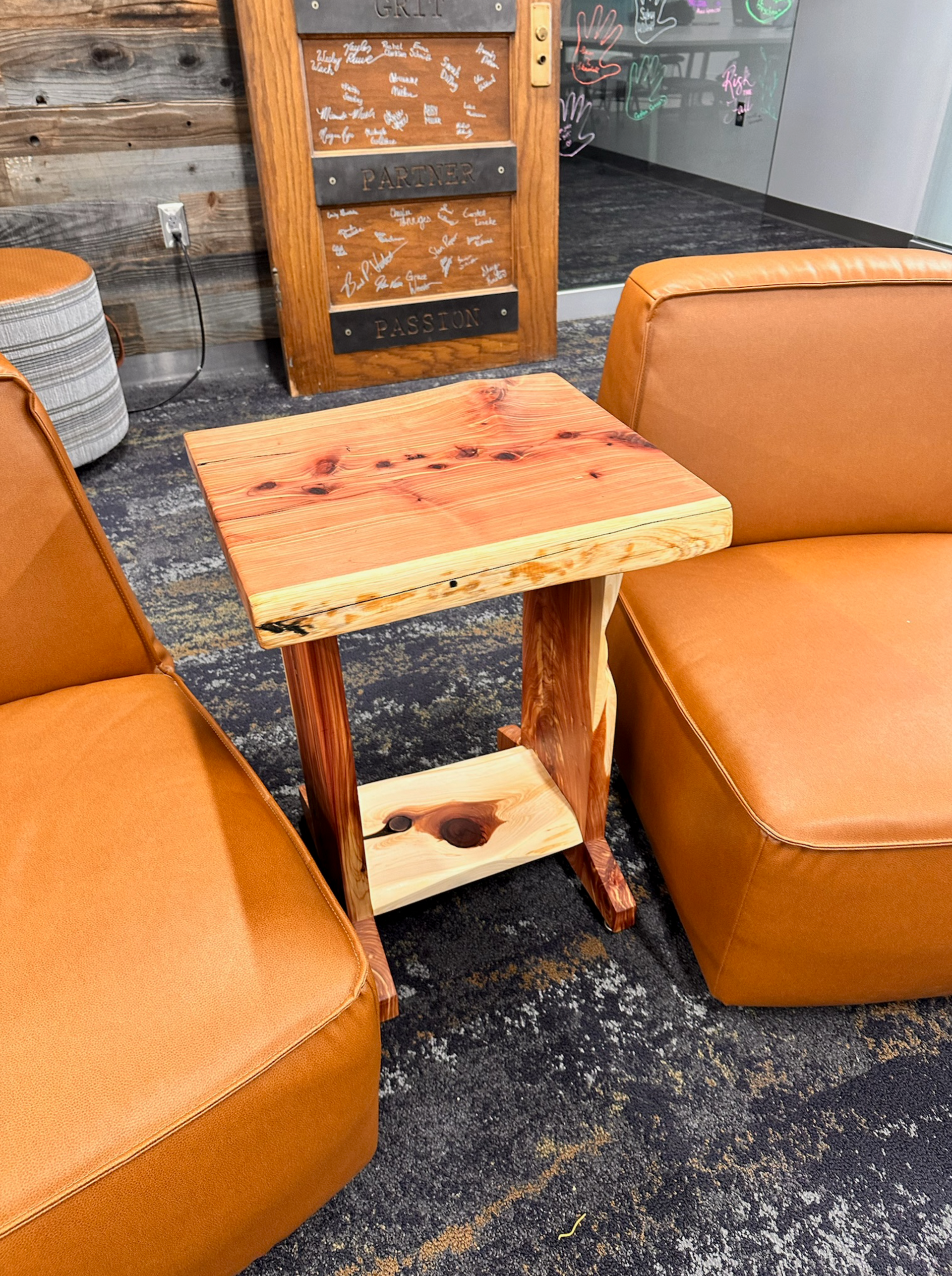 Rustic wooden side table between two orange leather armchairs.