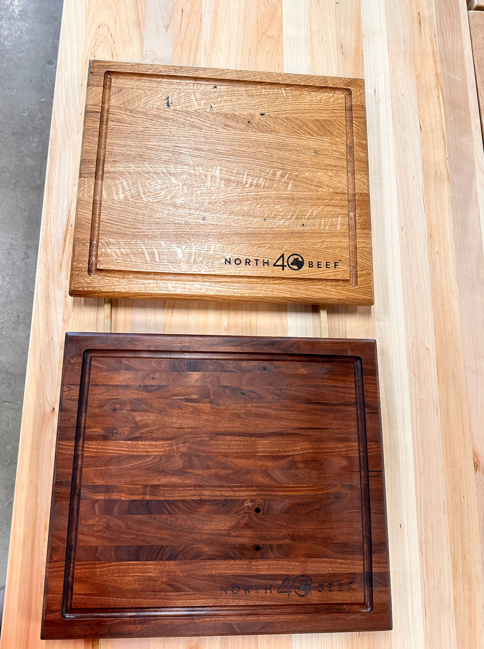 Two wooden cutting boards, one light, one dark, with juice grooves and engraved text.