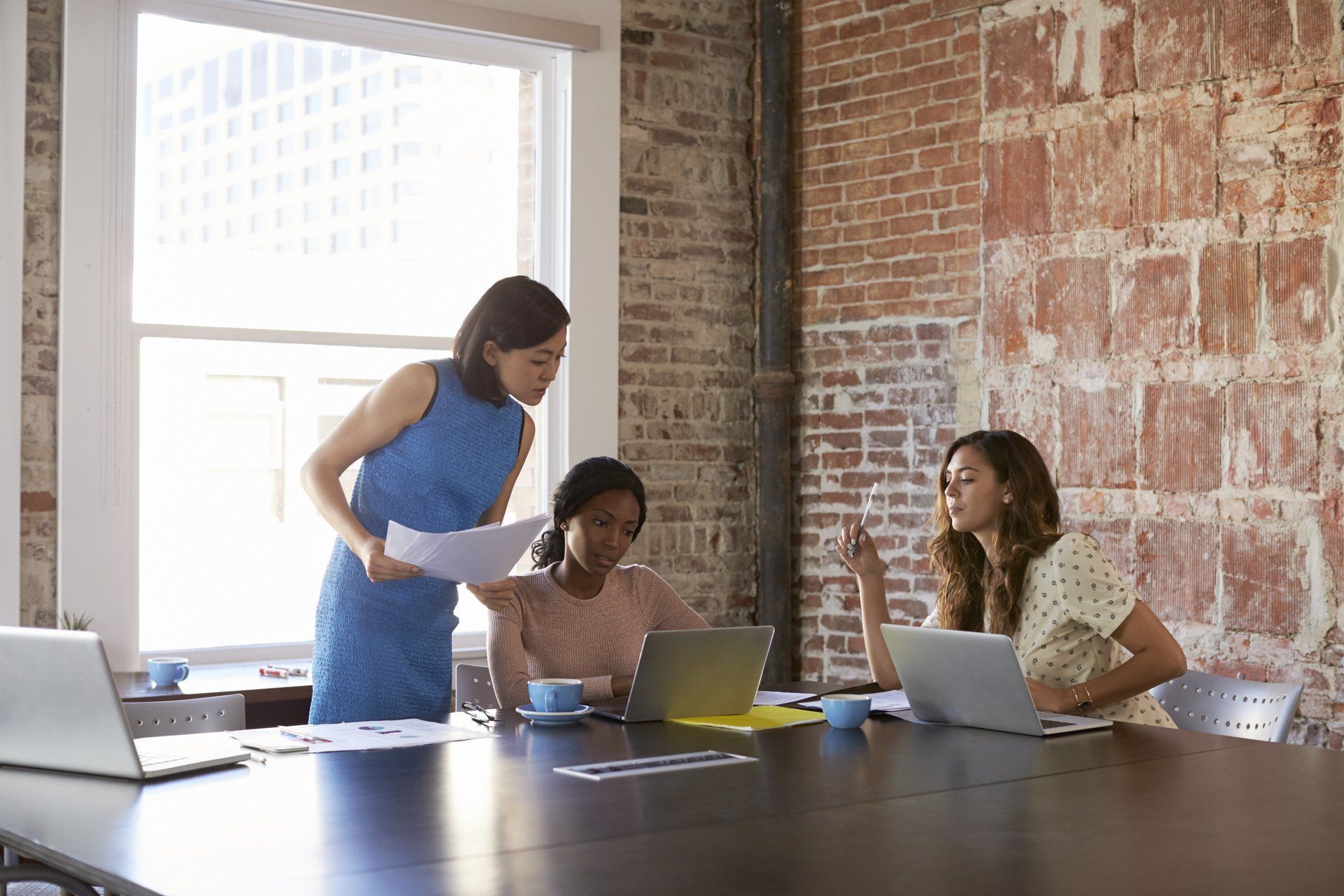 Three Women Working Around a Boardroom Table