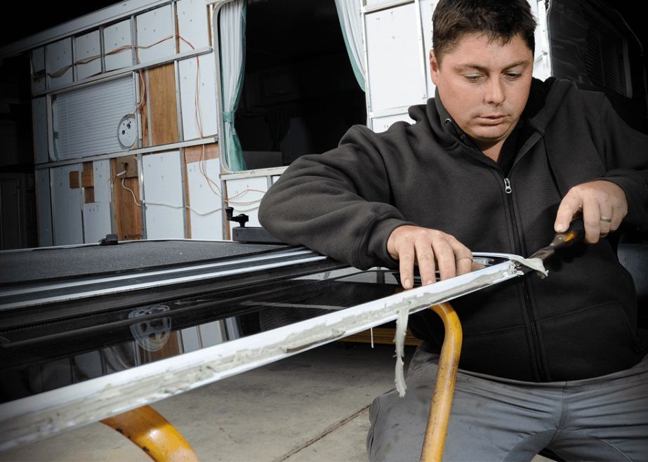 A Man in a Black Jacket is Working on a Piece of Metal — Capital Caravans Pty Ltd In Raleigh, NSW
