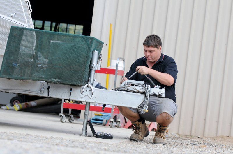 A Man is Working on a Trailer in Front of a Building — Capital Caravans Pty Ltd In Raleigh, NSW