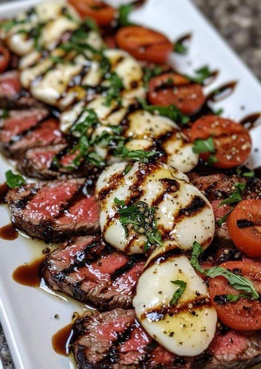 A white plate topped with steak , mozzarella and tomatoes.