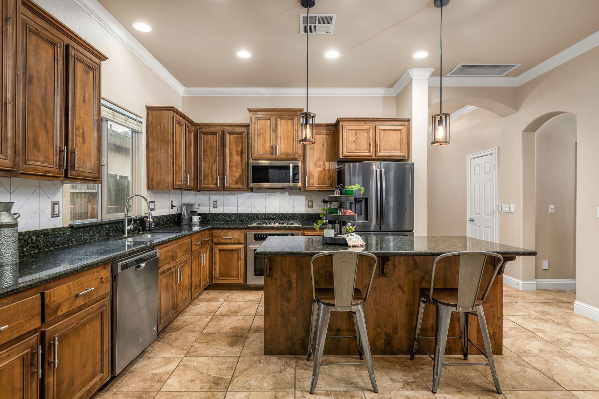 Kitchen with granite counters, island seating, and dining space in a luxury home on La Guardia Circle.