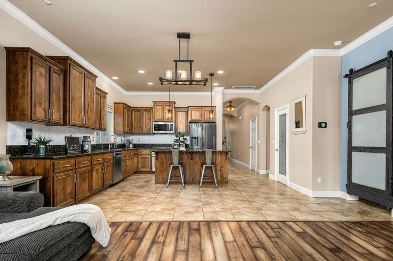 Kitchen on La Guardia Circle with wood cabinets, stainless appliances, an island, and a barn door.