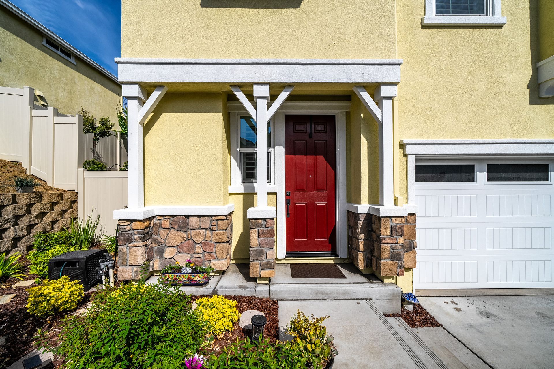 Welcoming front porch with bold red door, stone accents, and neat landscaping listed by a top realtor, Nicole Spencer.