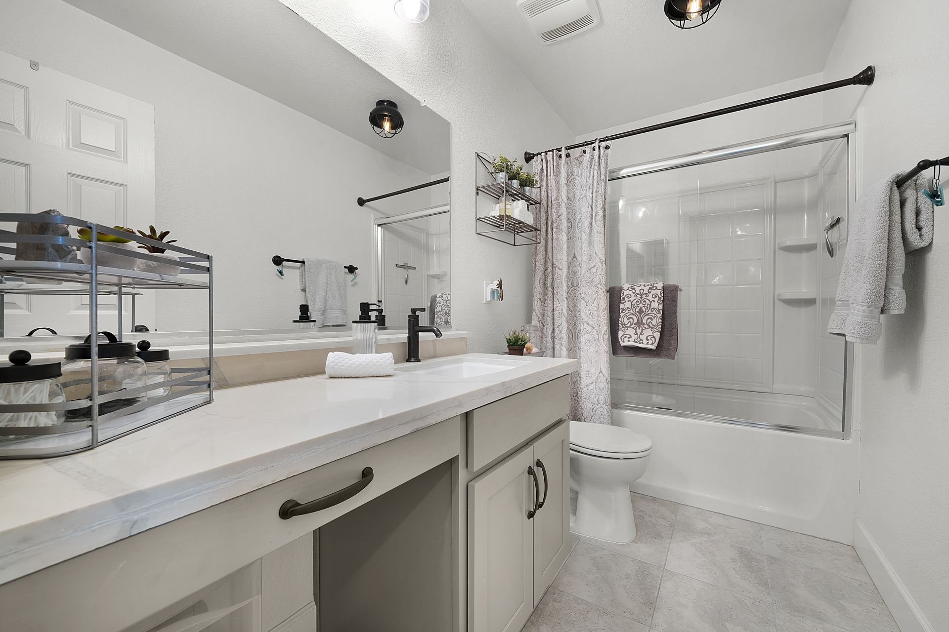 Bright bathroom with double-sink vanity, full tub and shower combo, and sleek white countertops.