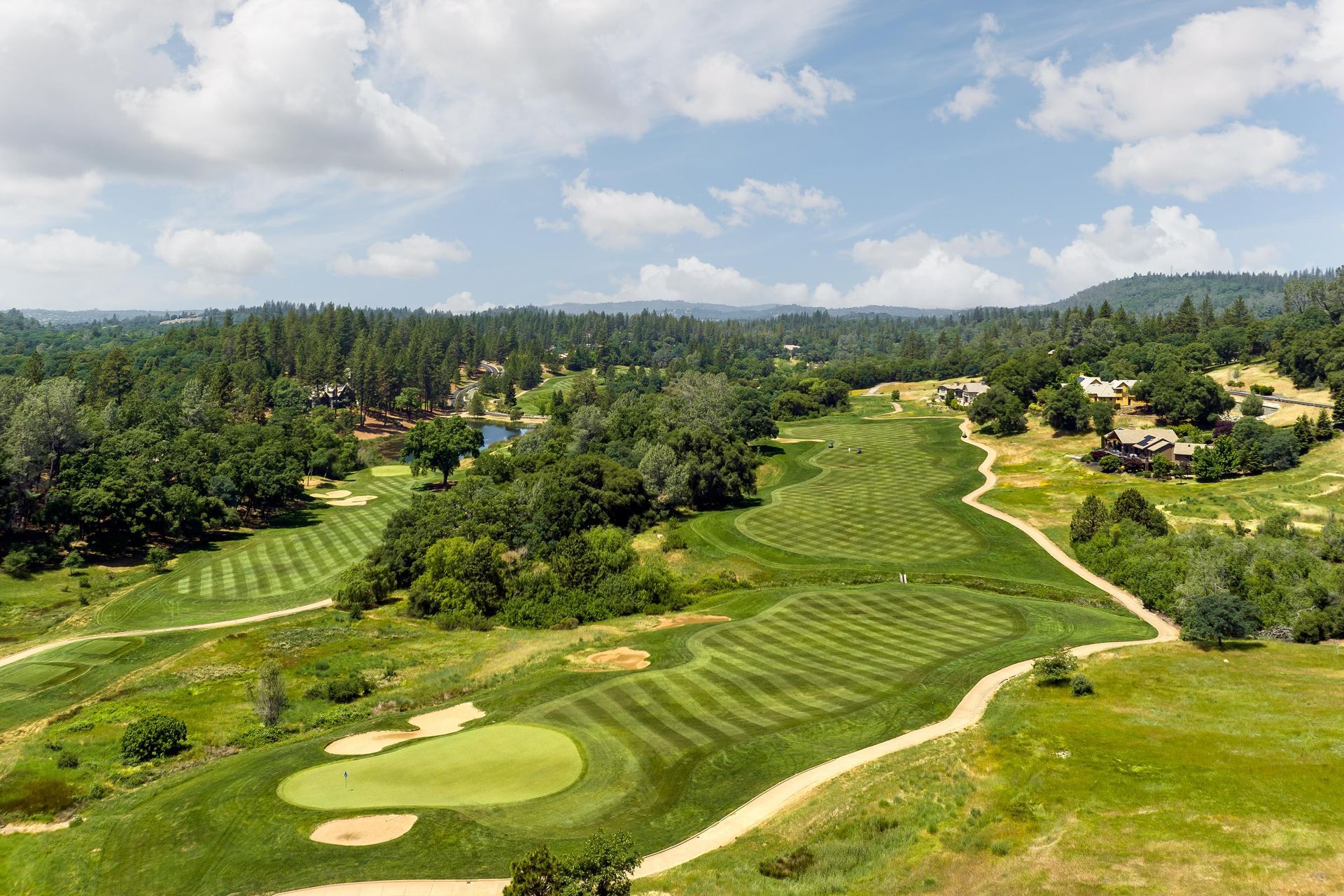 An aerial view of a golf course surrounded by trees and grass.