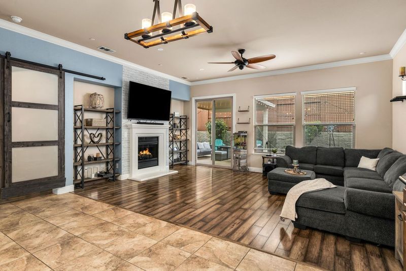 Spacious living area with large windows, wood floors, and patio access in a luxury home on La Guardia Circle.