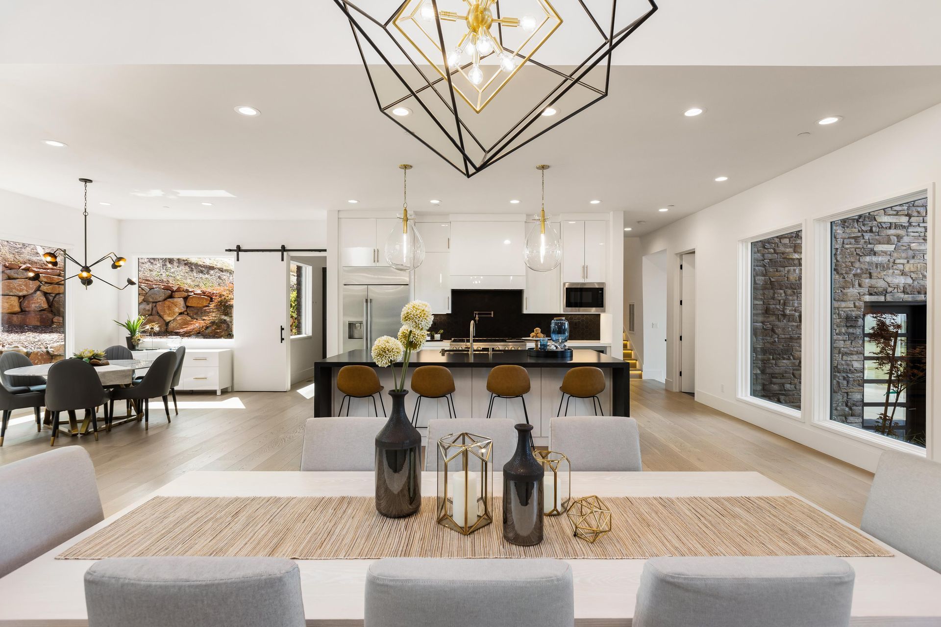 A dining room with a table and chairs and a kitchen in the background | Luxury Homes
