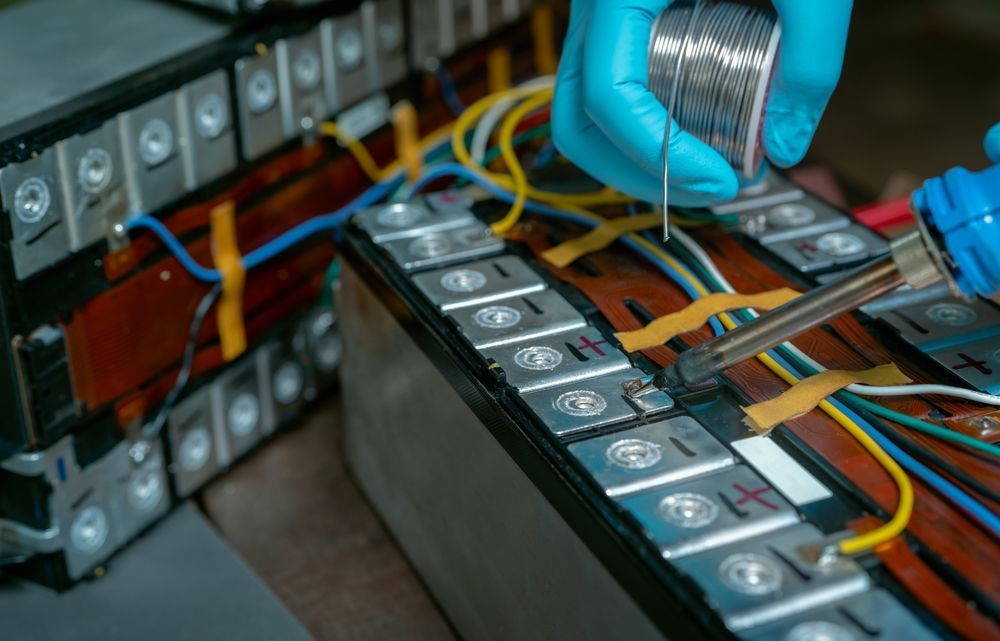 A person is soldering a battery with a soldering iron.