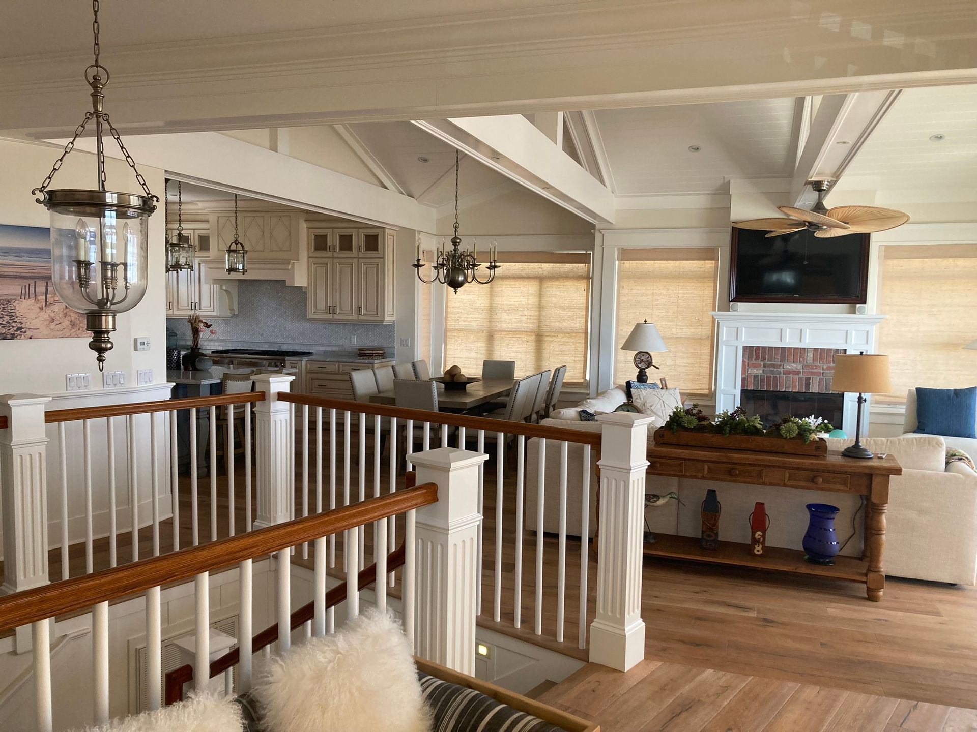 Open-concept living space with kitchen, dining area, and living room, white walls, wood floors, and a staircase.
