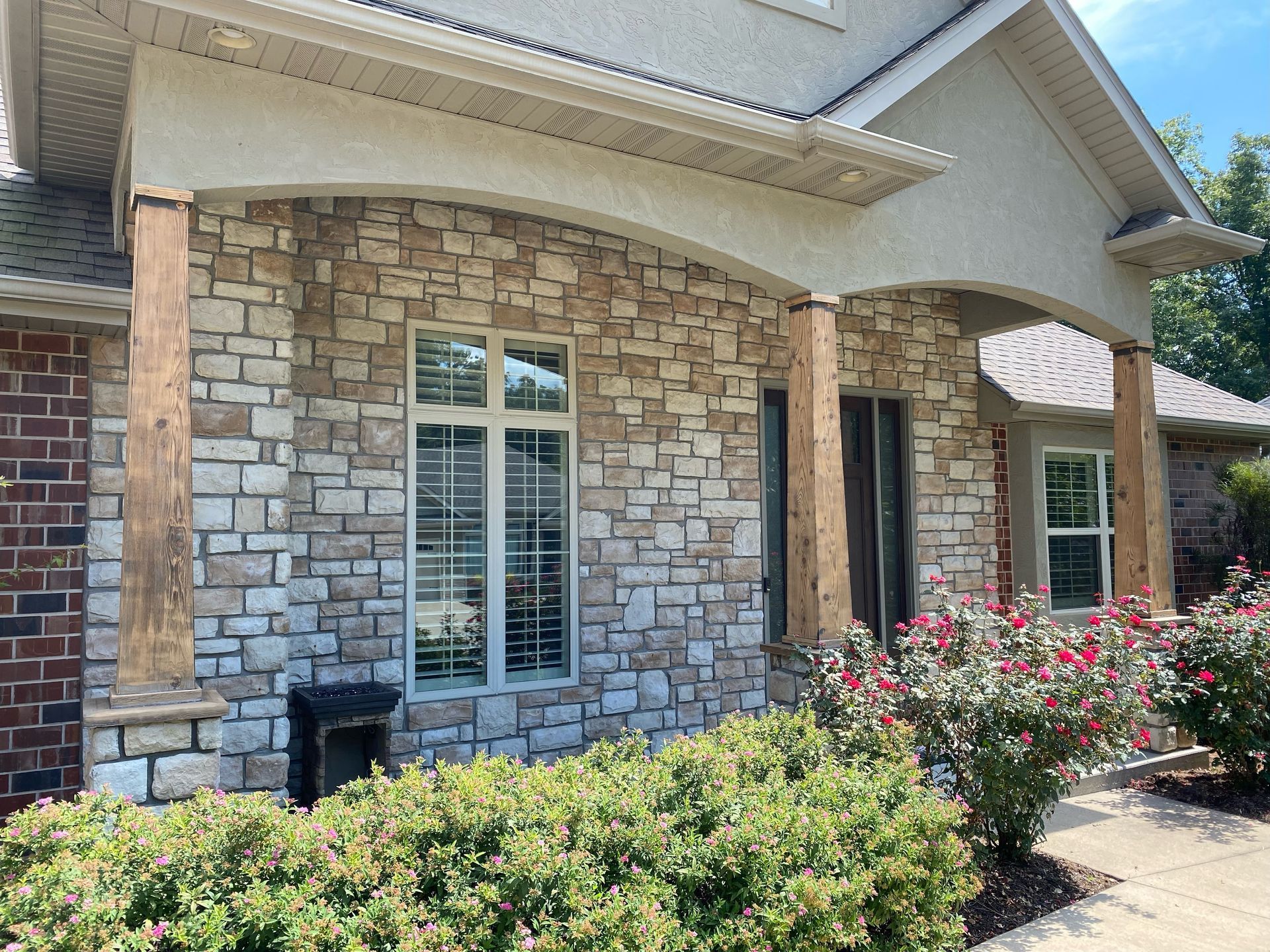 The front of a brick house with a porch and a lot of windows.