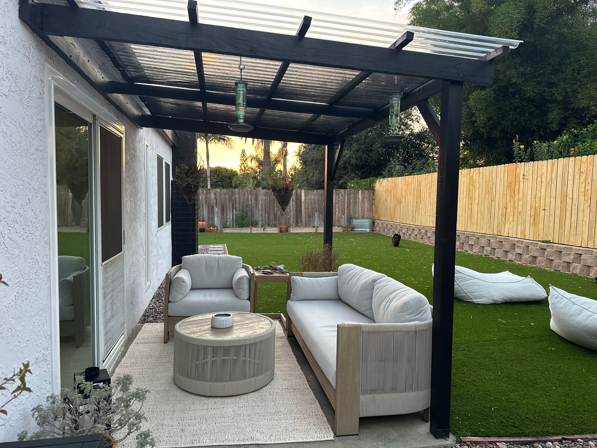 A patio with a couch and chairs under a pergola