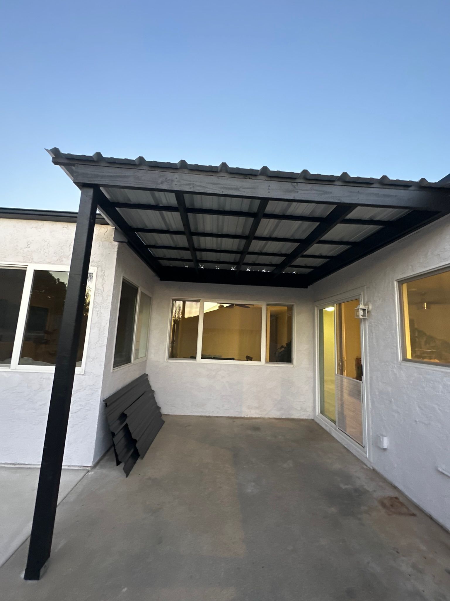 A white house with a black roof and a covered patio.