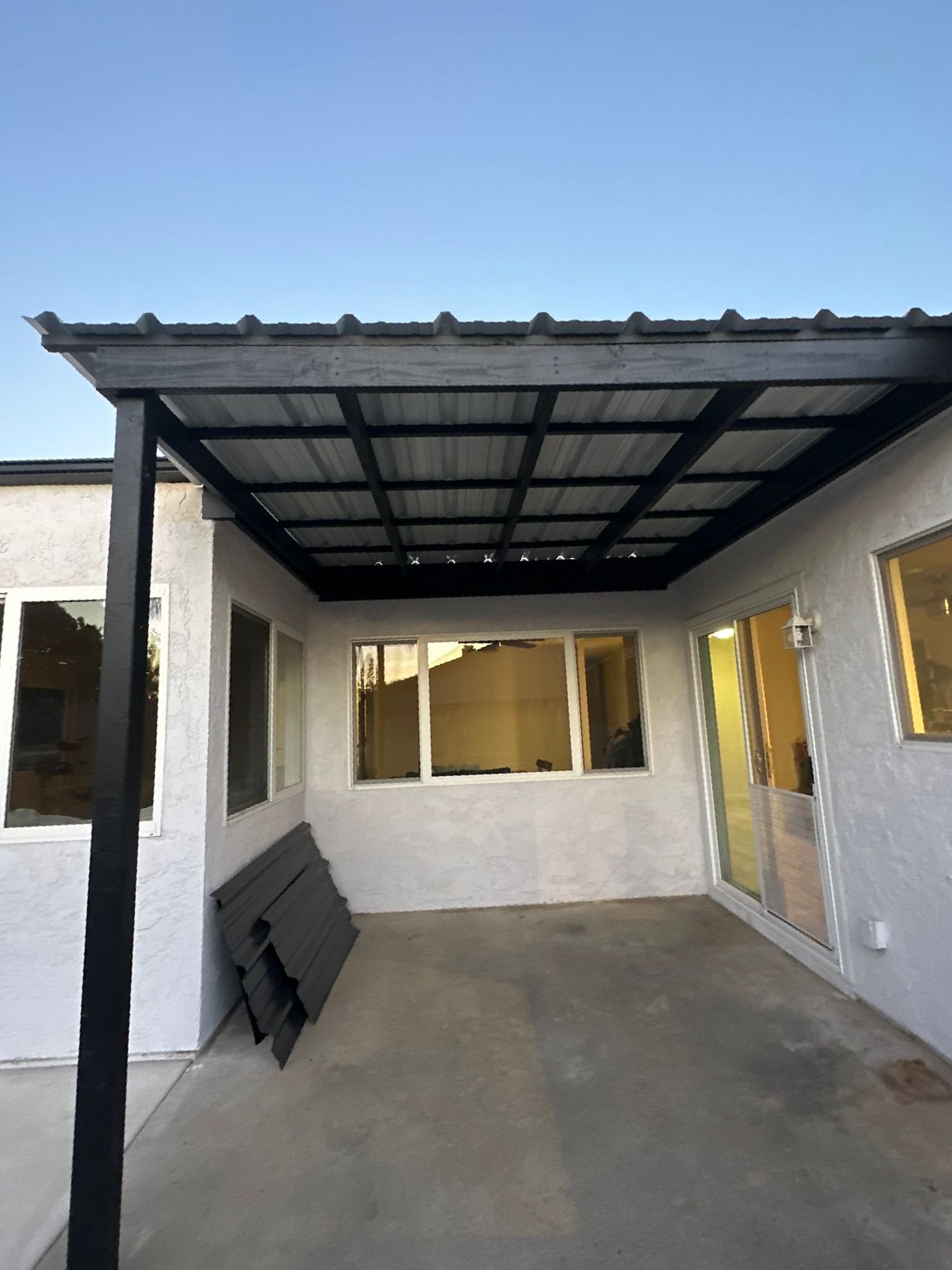 A white house with a black roof and a covered patio.