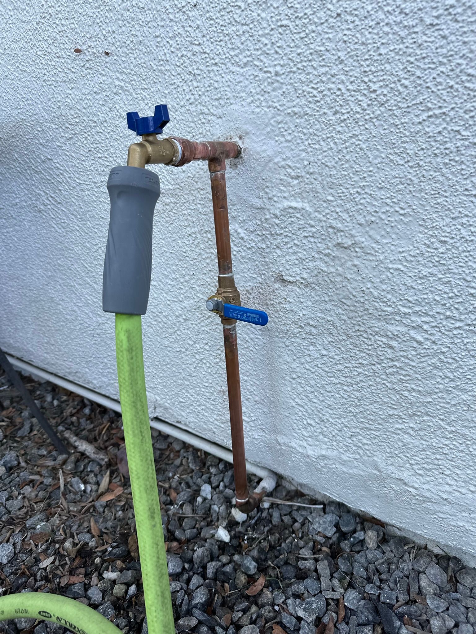 A hose is attached to a faucet on the side of a building.