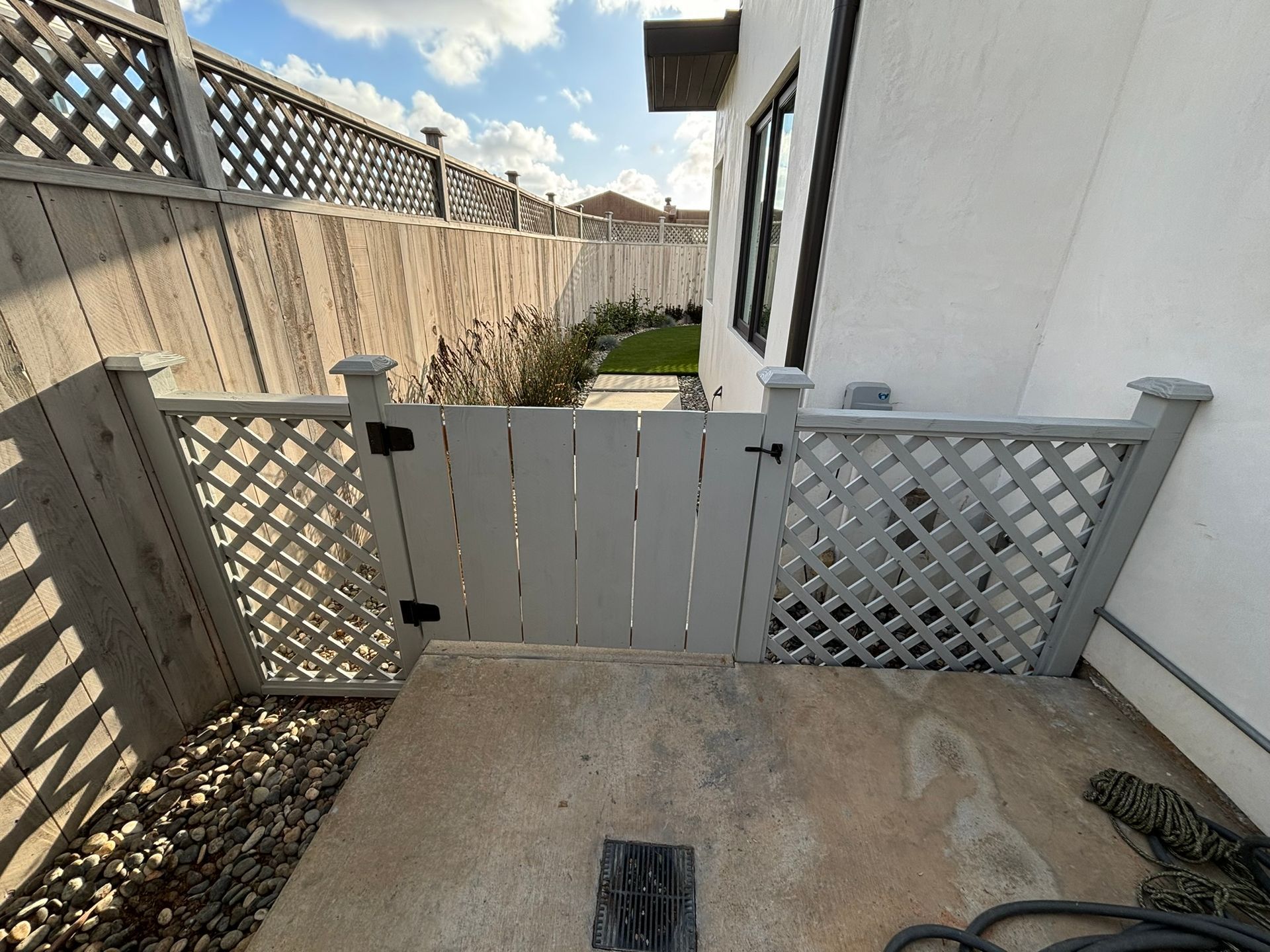 A white fence with a gate leading to a backyard.
