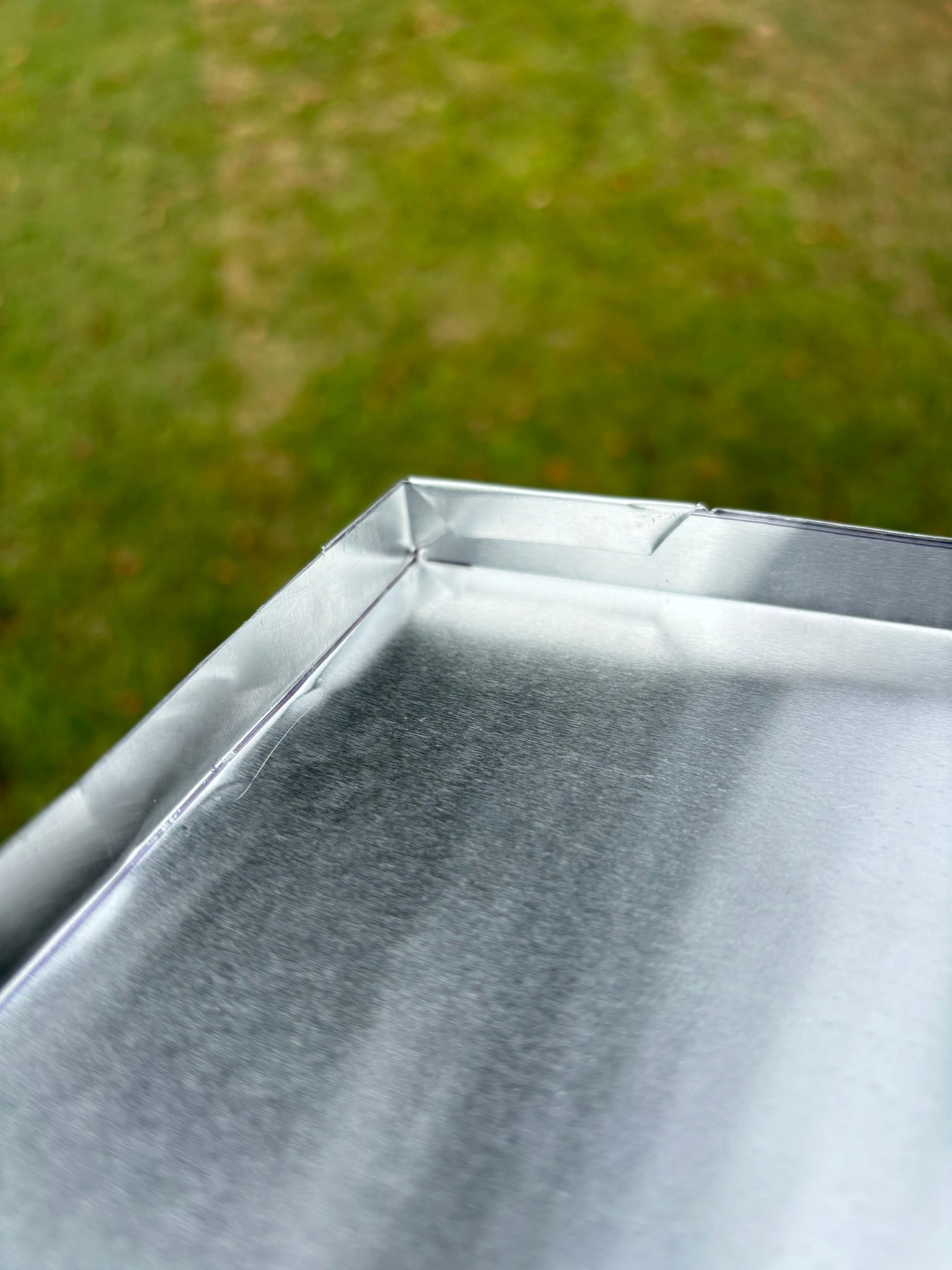 A close up of a metal surface with a green background.