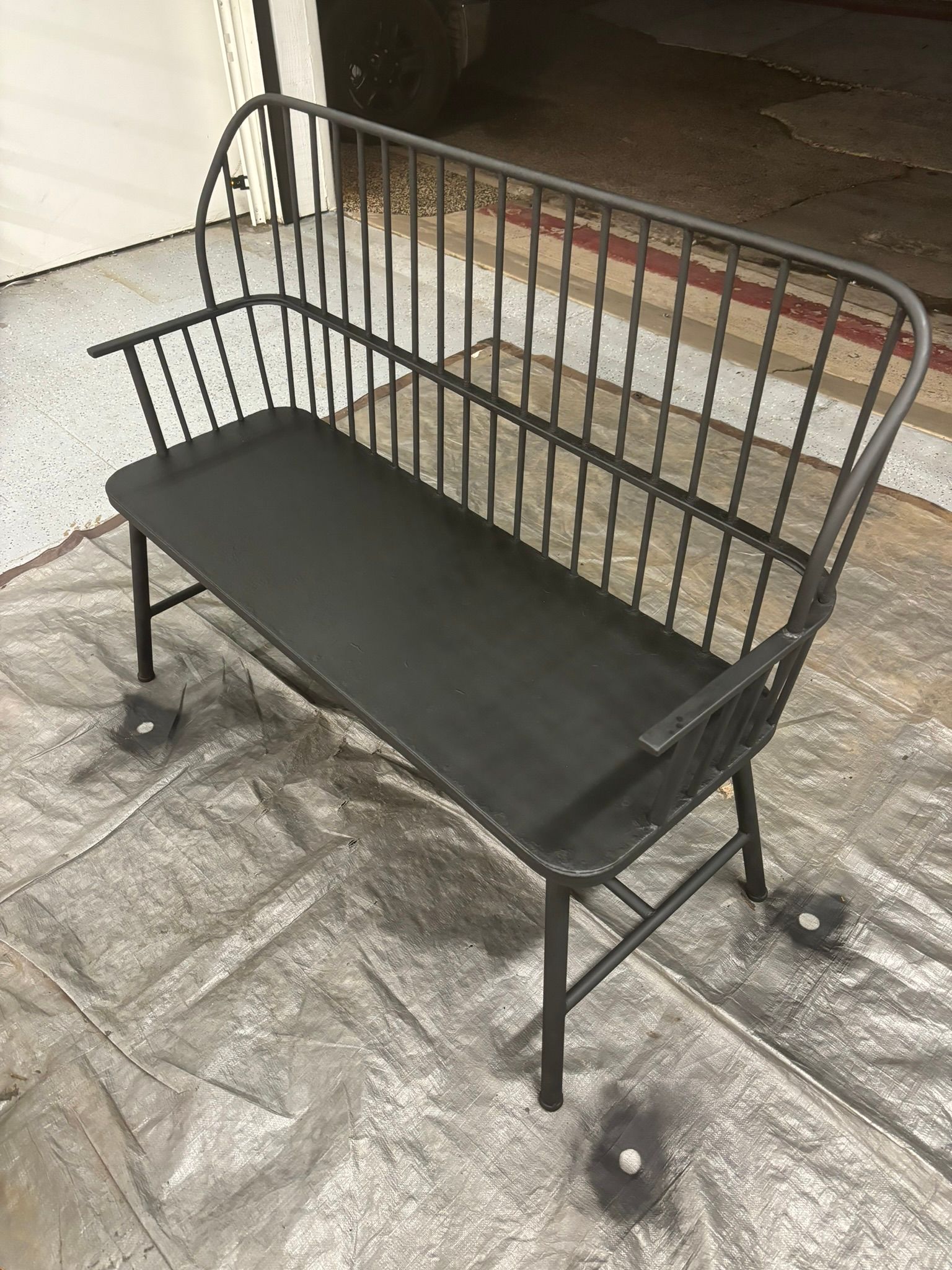 A black bench is sitting on top of a concrete floor.