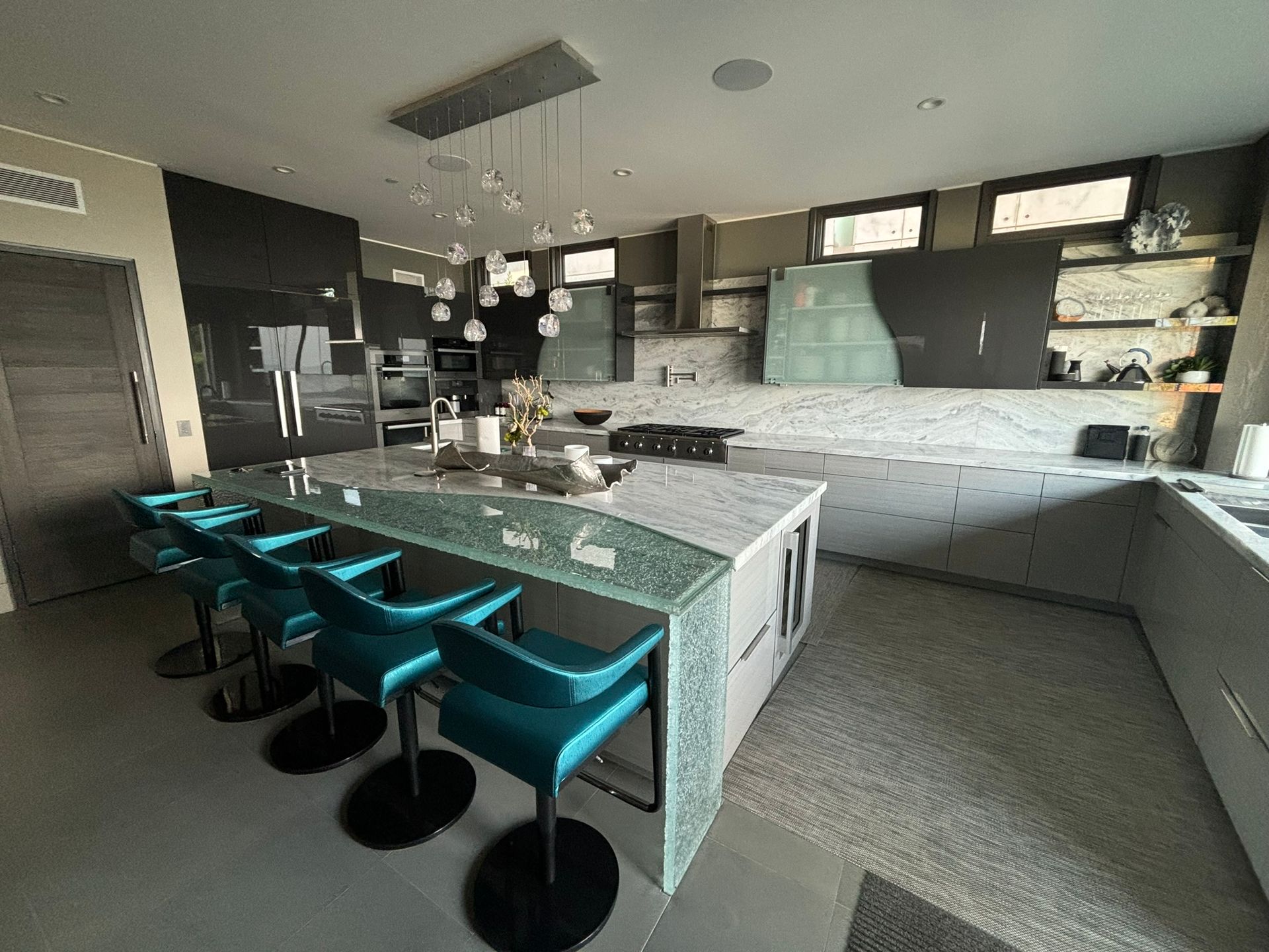 A kitchen with a large island and stools in it.