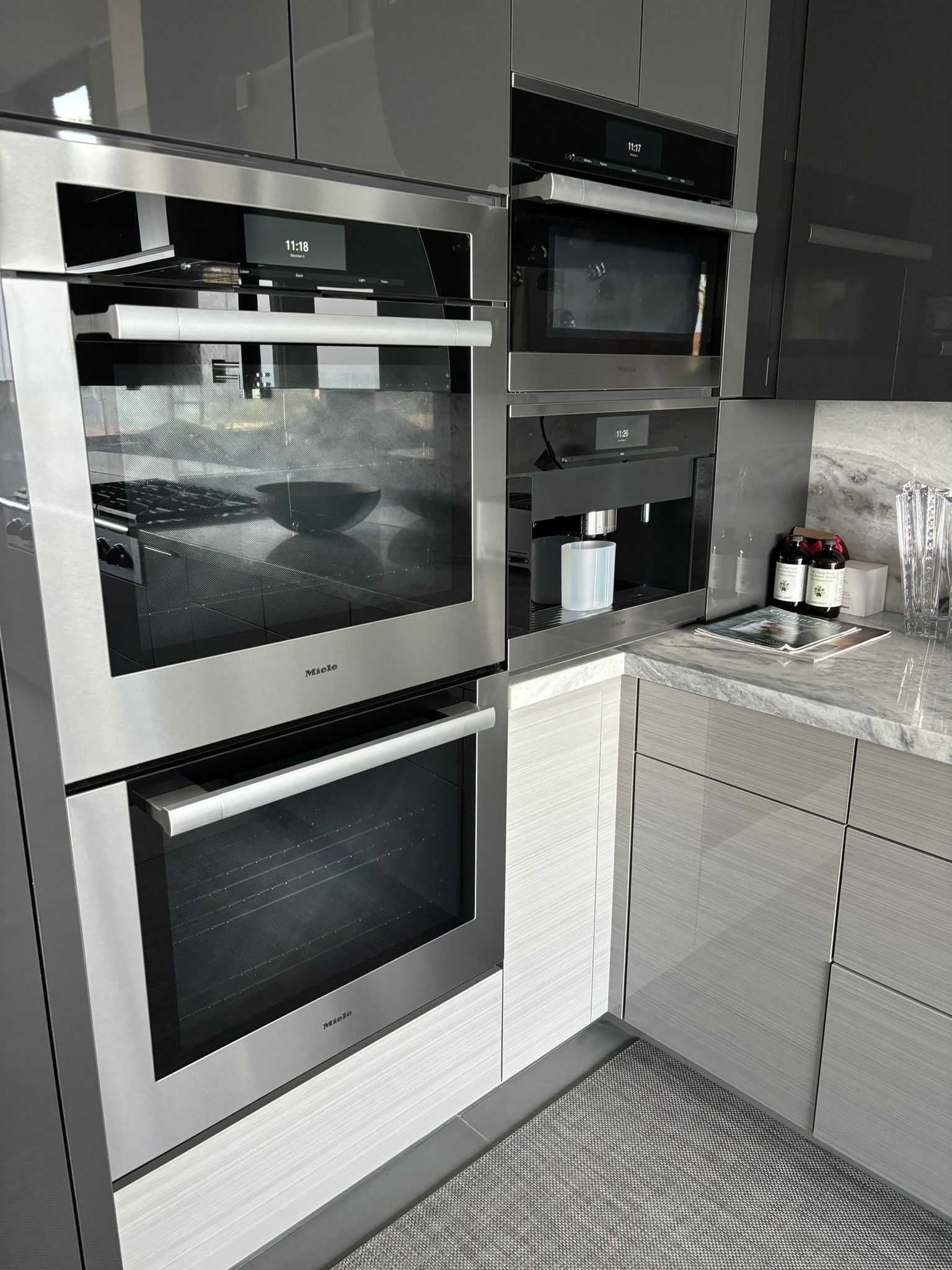 Built-in stainless steel double ovens, microwave, and coffee maker in a modern gray kitchen corner.