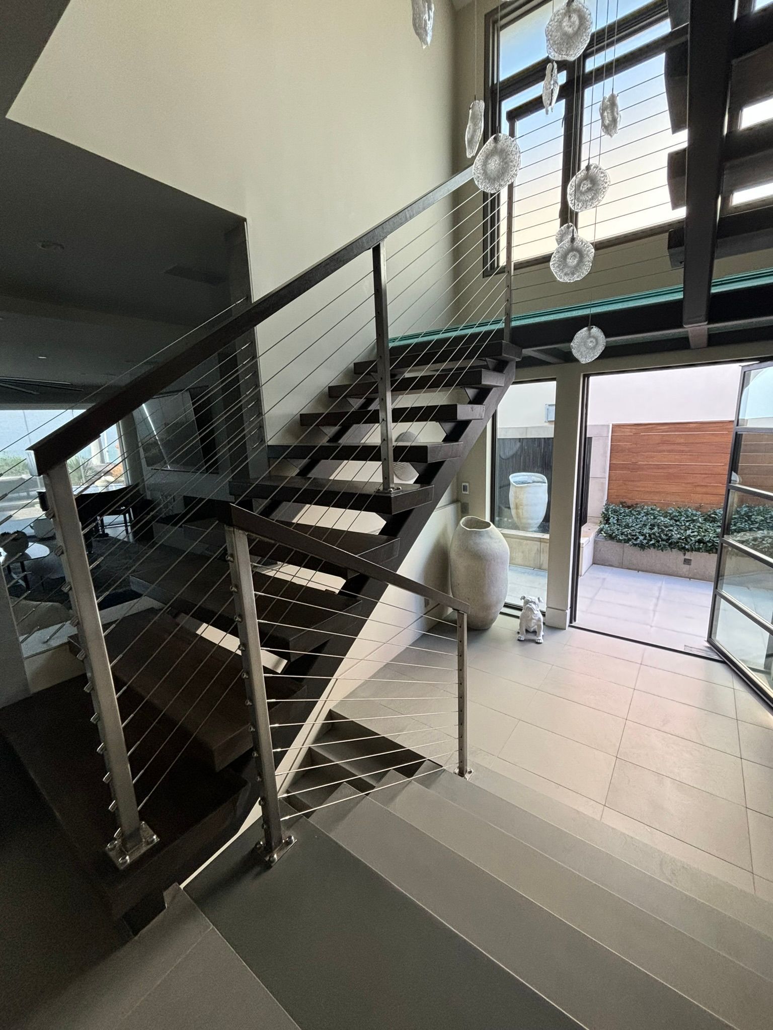 Modern staircase with open treads, metal railings, and natural light.