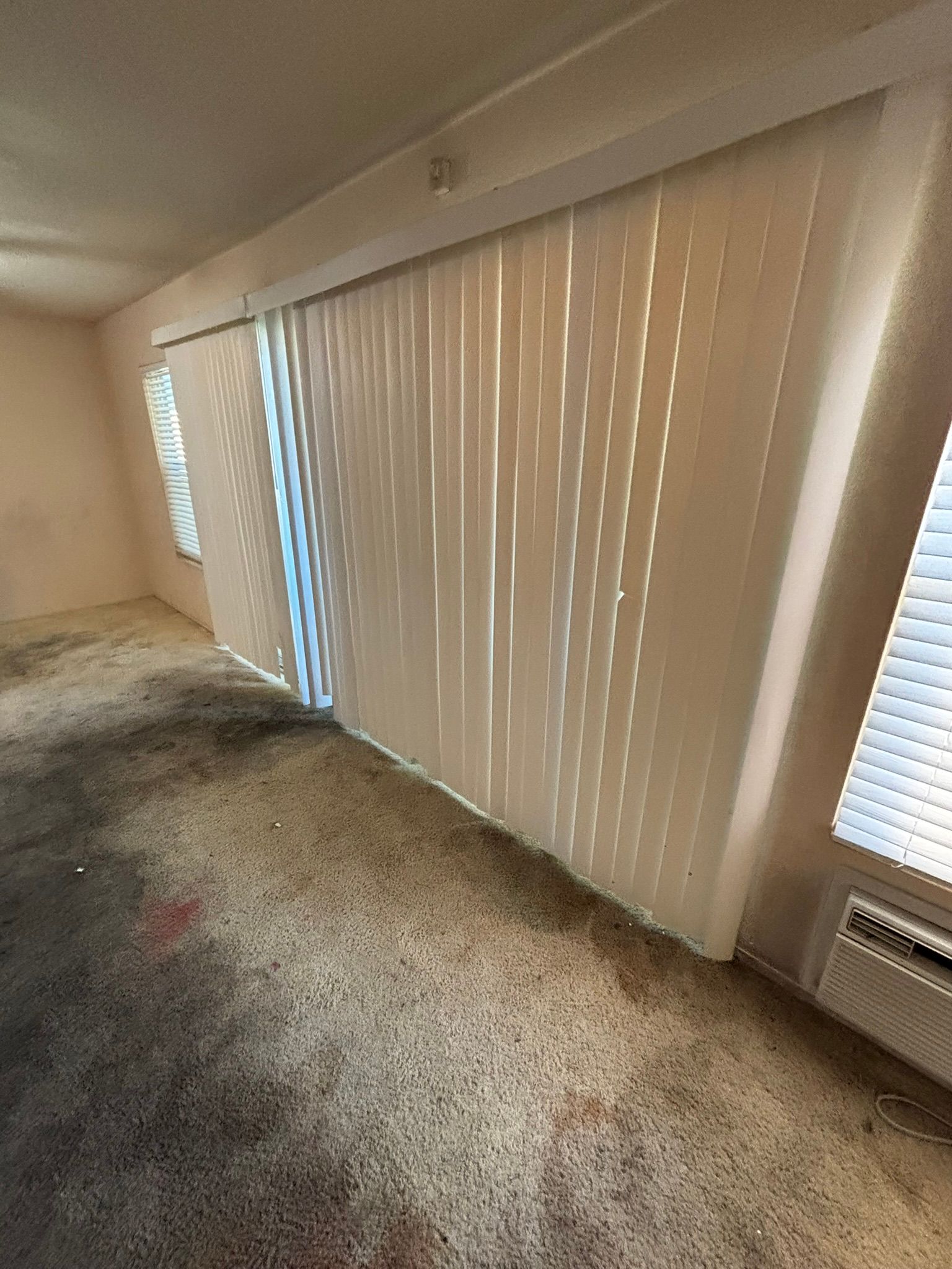 A living room with a sliding glass door and blinds.