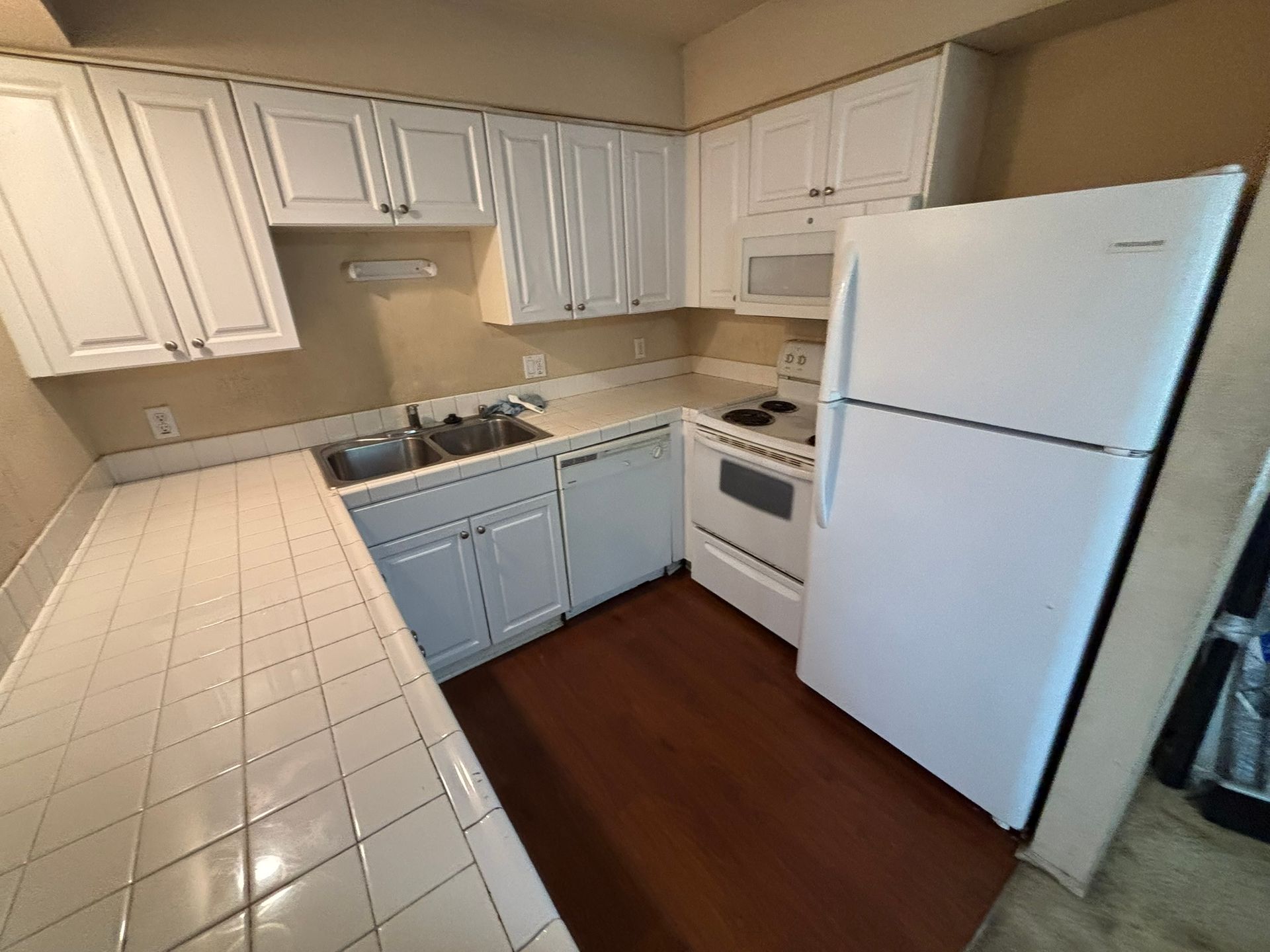 A kitchen with white cabinets , a refrigerator , stove , sink and microwave.