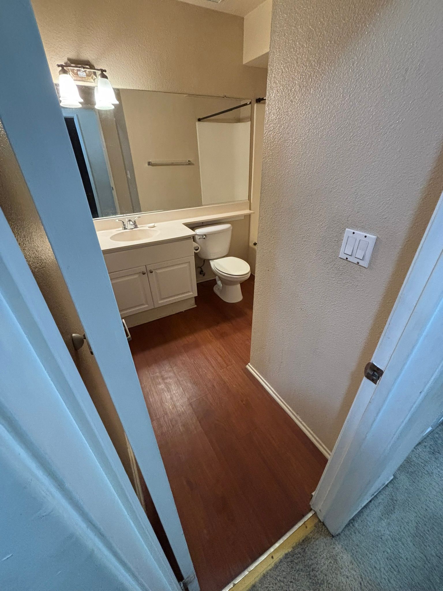 A bathroom with a toilet , sink and mirror.