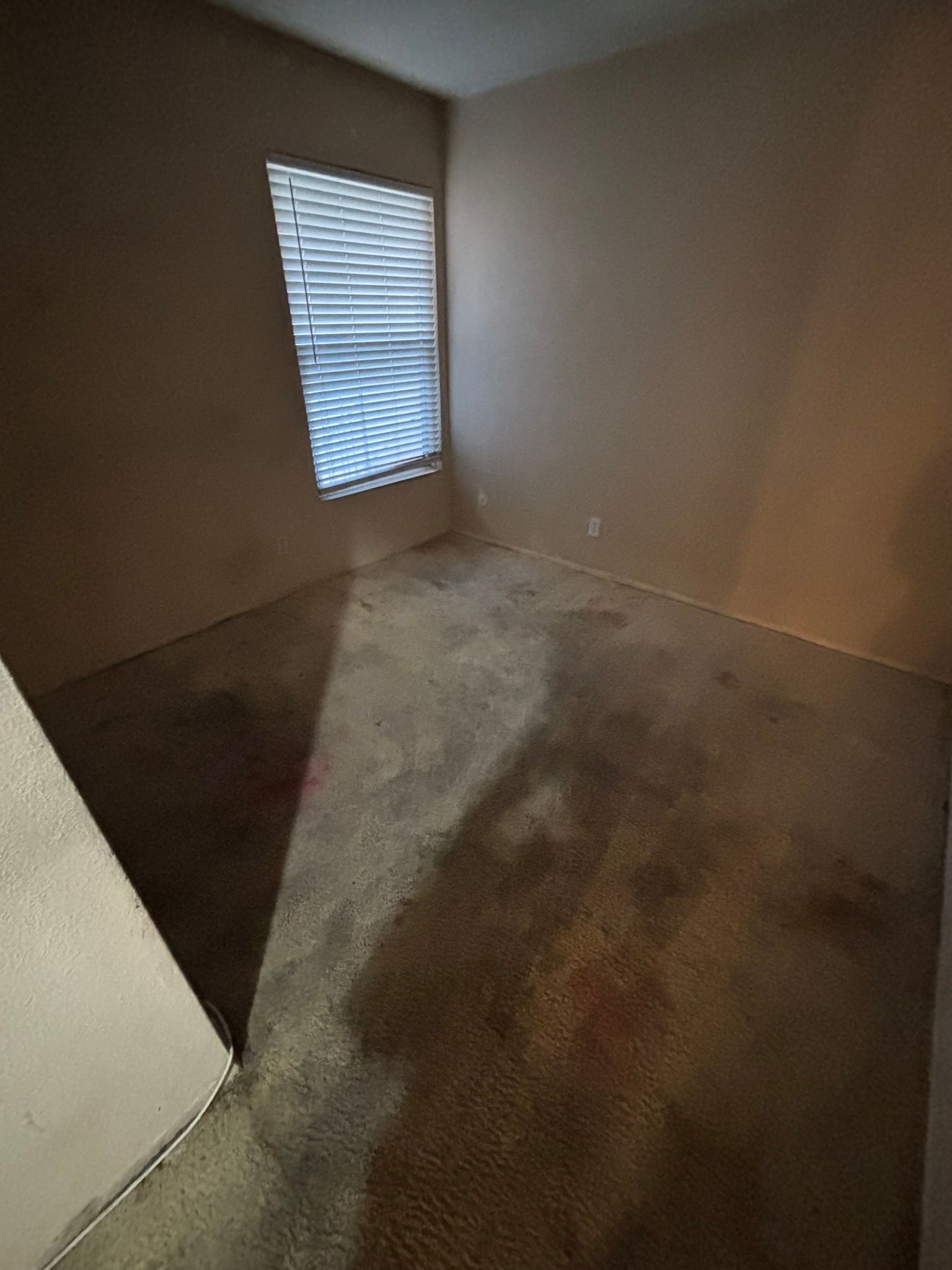 An empty bedroom with a window and blinds.