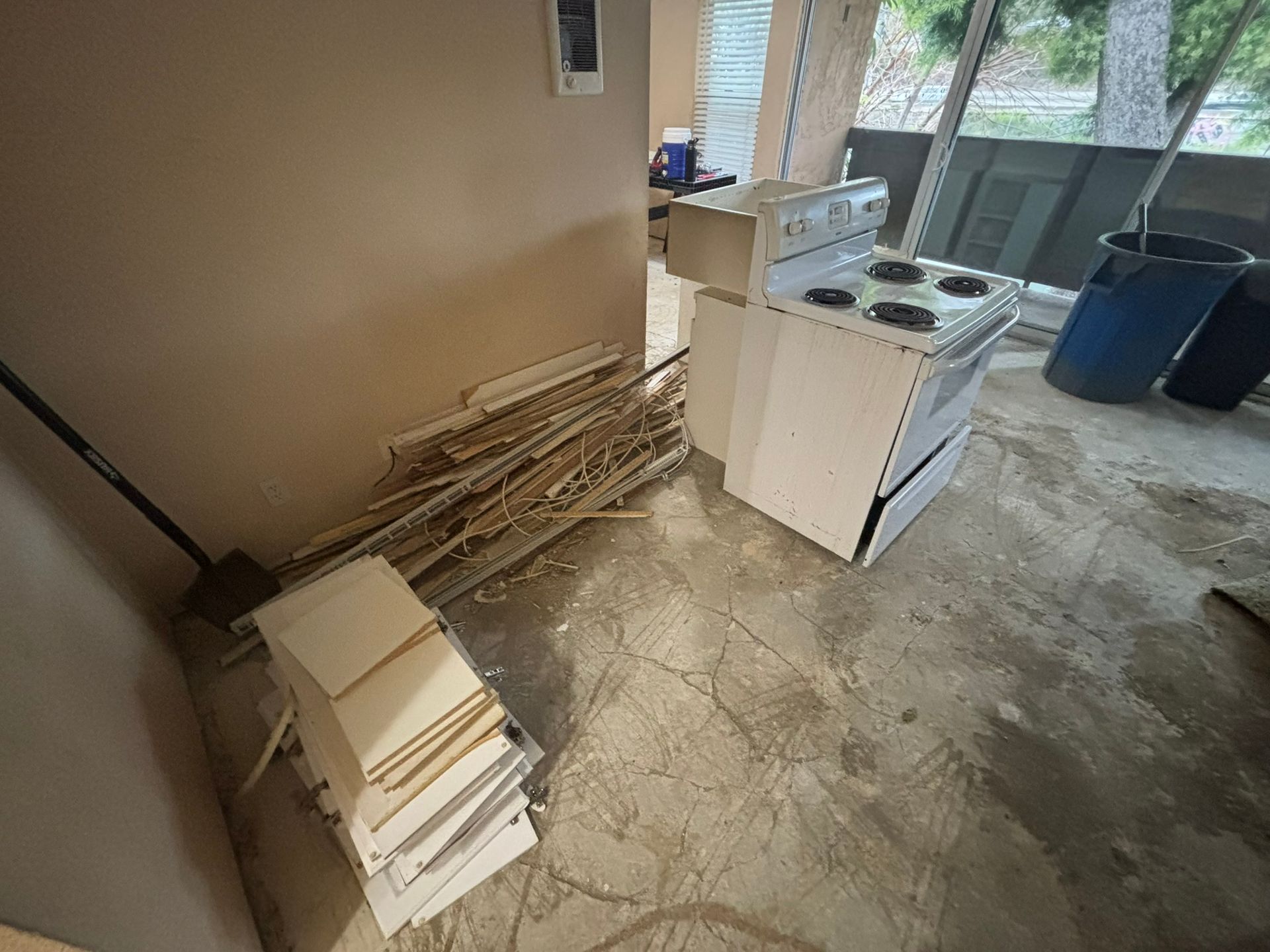 A kitchen with a stove and a bunch of junk on the floor.