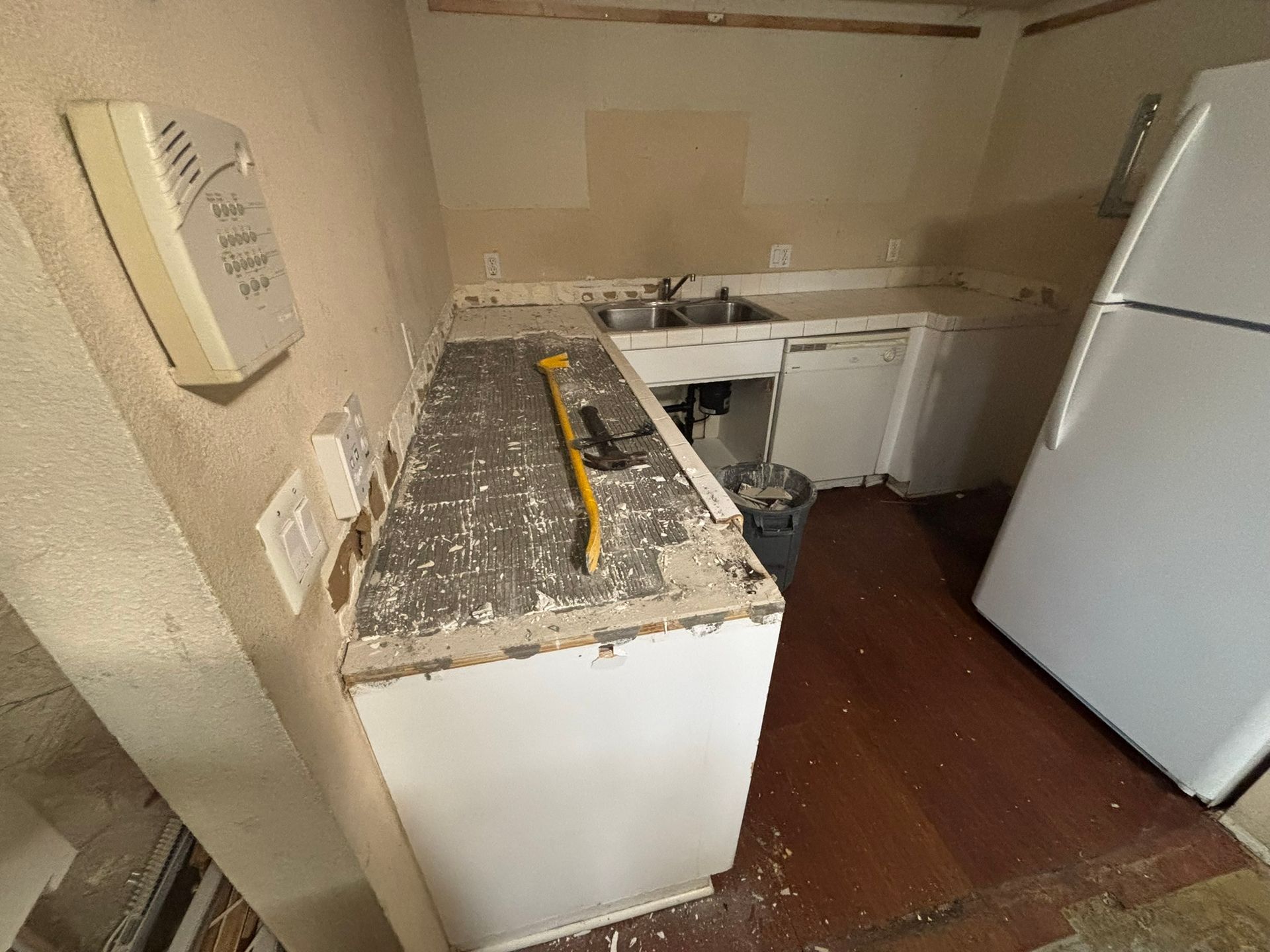 A kitchen with a sink , refrigerator , and cabinets being remodeled.