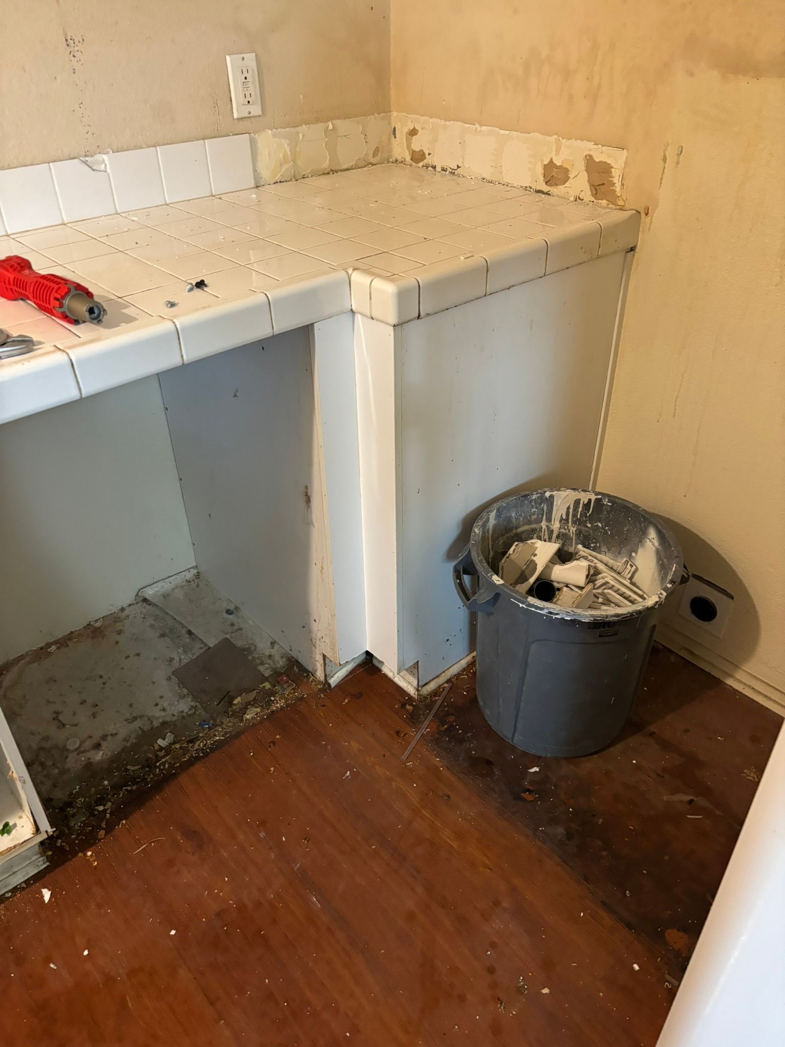 A dirty kitchen with a bucket of paint on the floor.