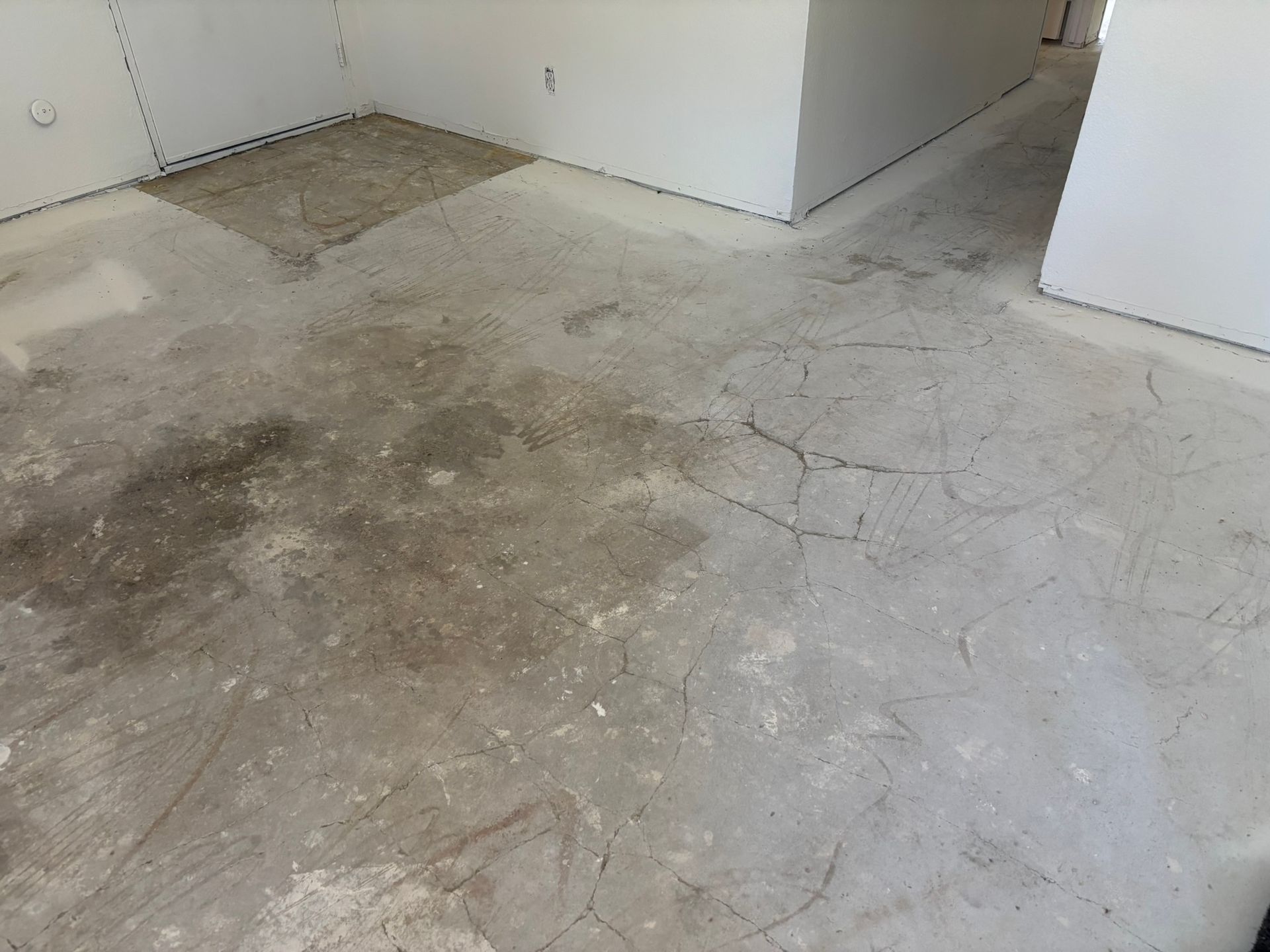 A dirty concrete floor in a room with white walls.