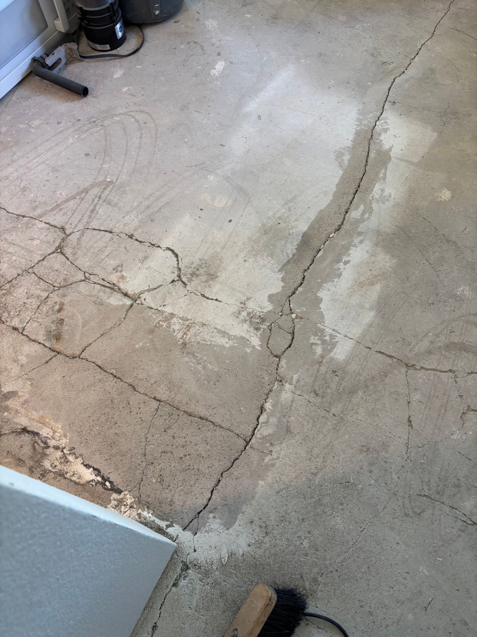 A close up of a cracked concrete floor with a broom.