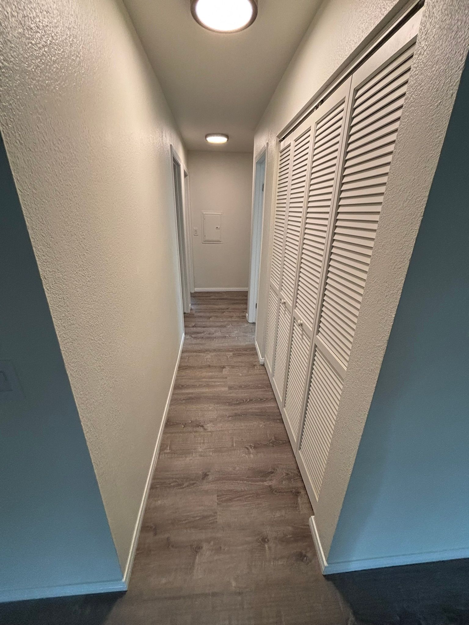 A long hallway with lots of closets and a light on the ceiling.