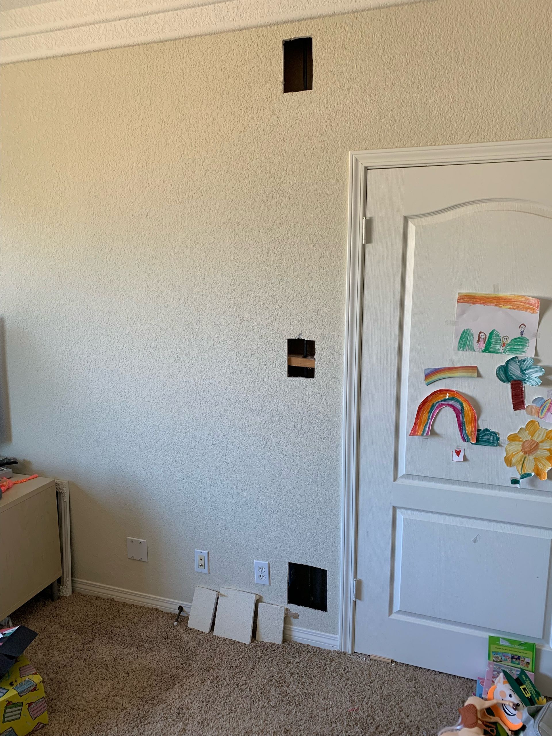A room with a door and a drawing of a rainbow on the wall.