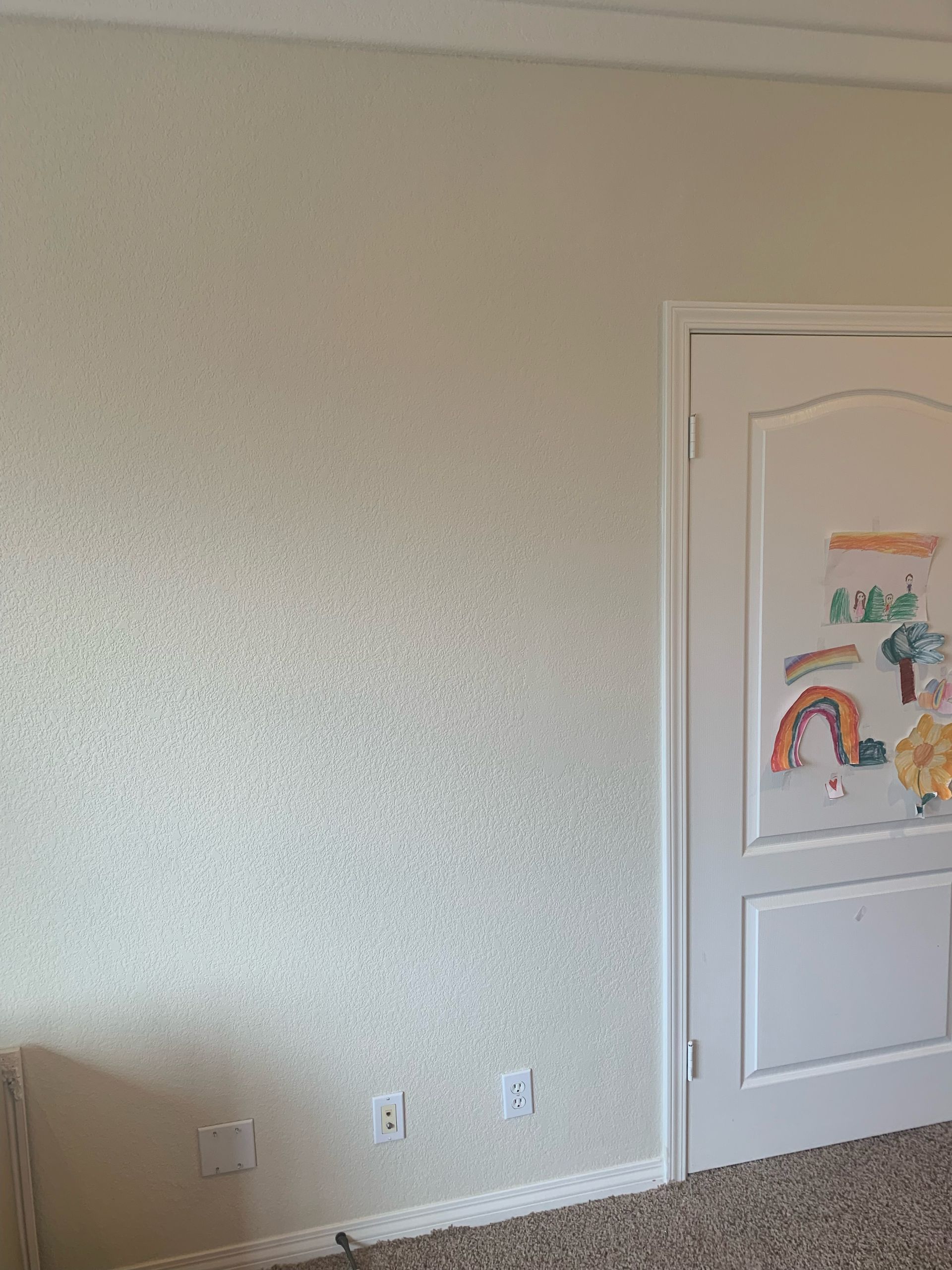 A room with a white door and a drawing on the wall.