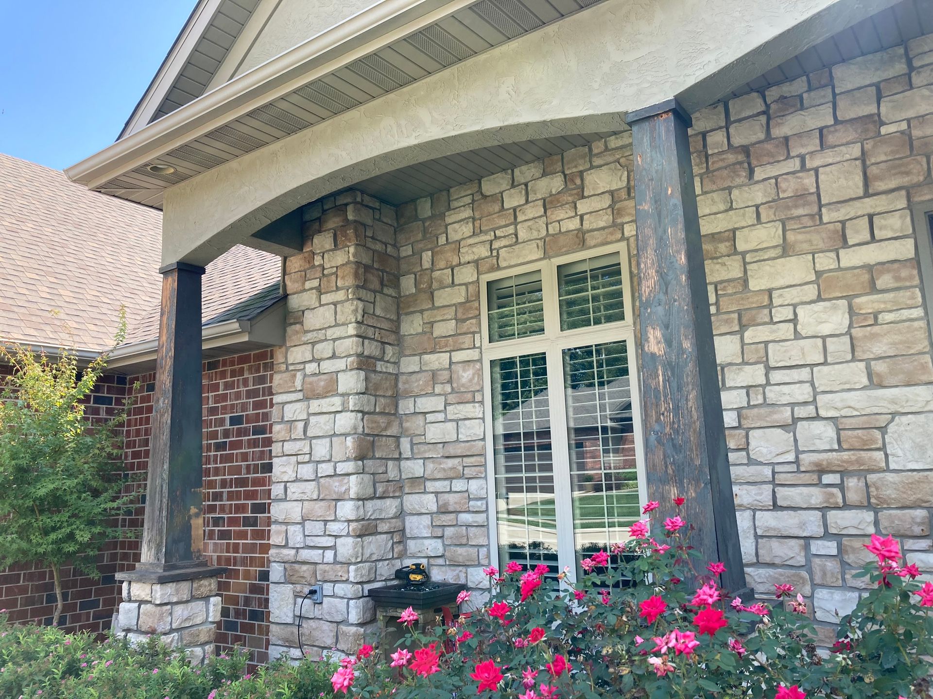 A stone house with a porch and flowers in front of it