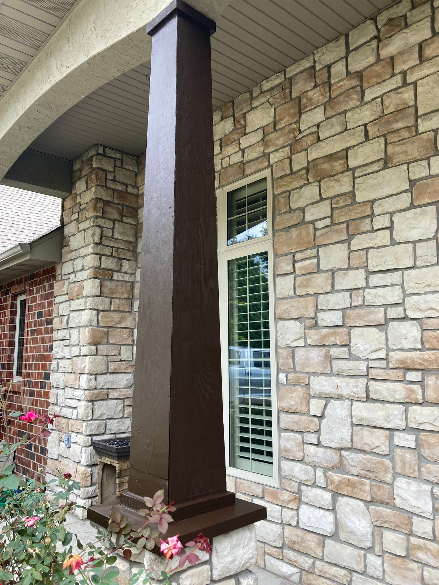 A brick wall with a pillar and a window on it.