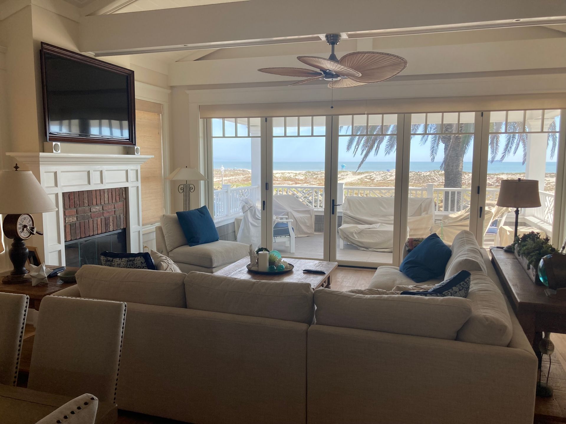 Living room with ocean view: cream-colored sectional sofa, fireplace, and sliding glass doors.