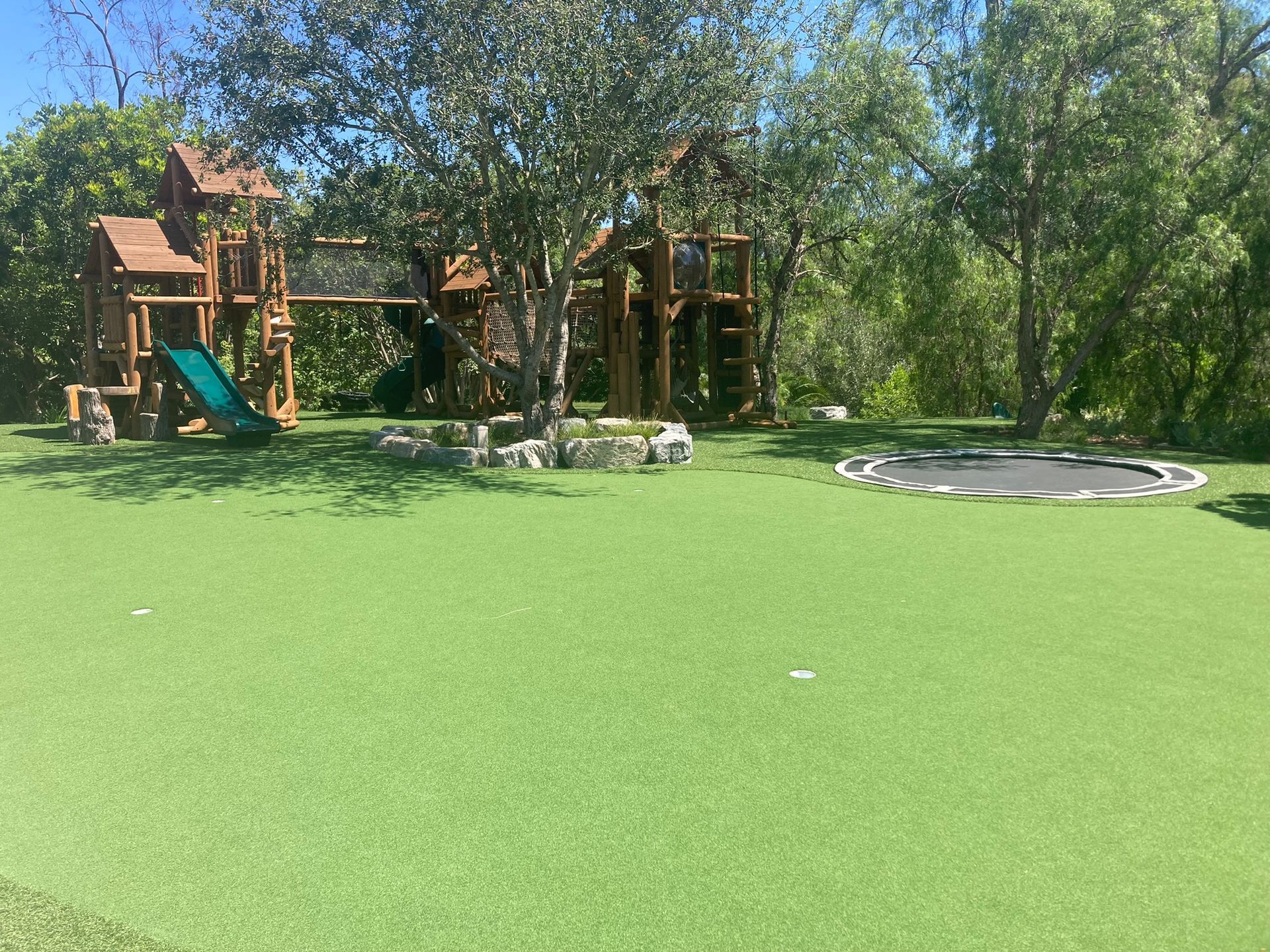 A playground with a slide and a trampoline in the middle of it.