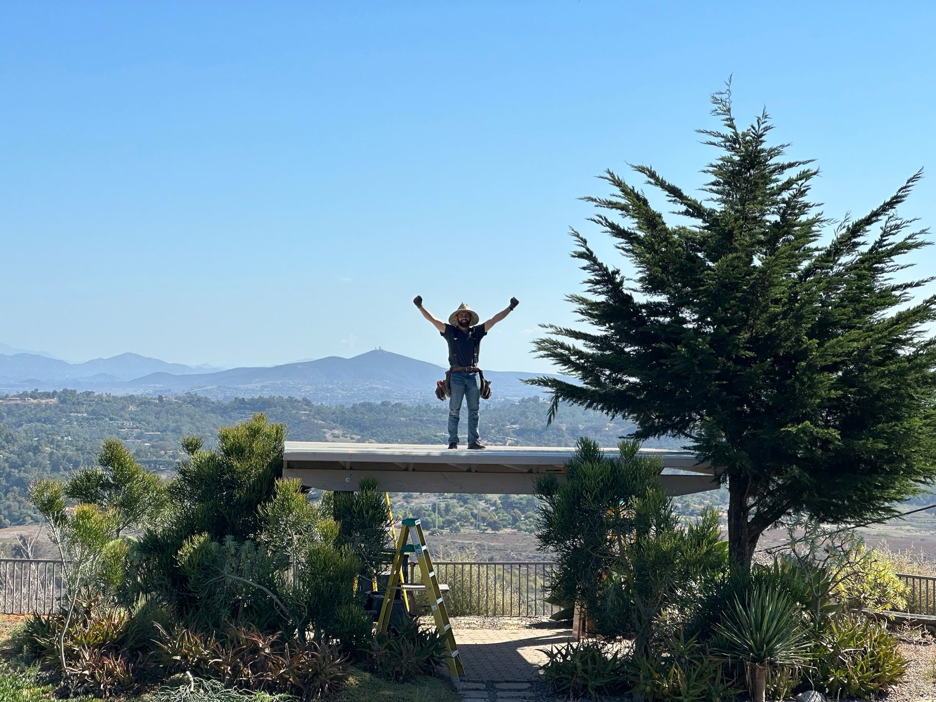 A woman is standing on top of a bridge with her arms outstretched.