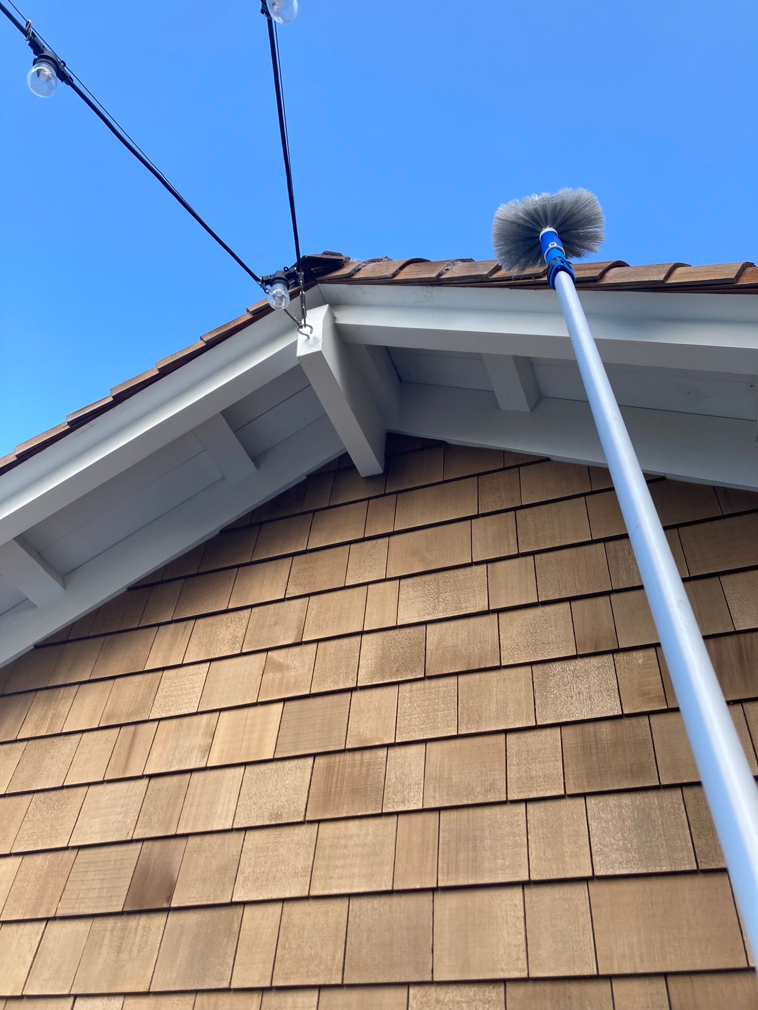 A roof cleaning pole with a brush on top of it