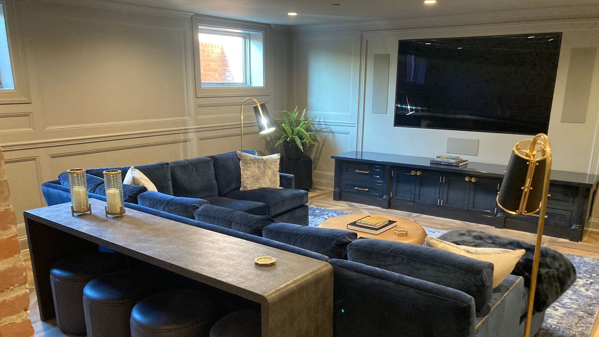 Cozy basement living room with navy blue sectional, large TV, and dark blue console.