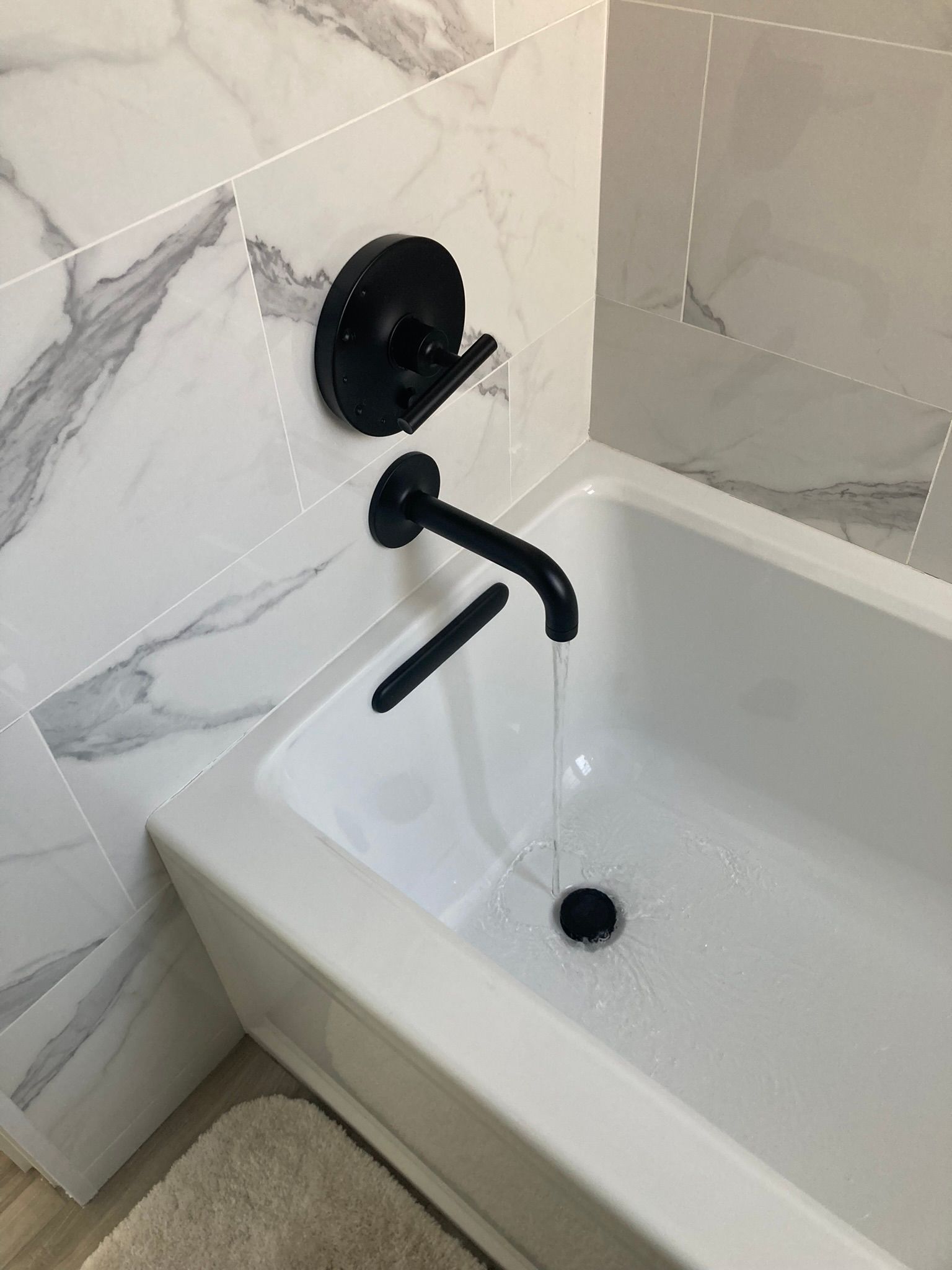 A white bathtub with a black faucet in a bathroom.