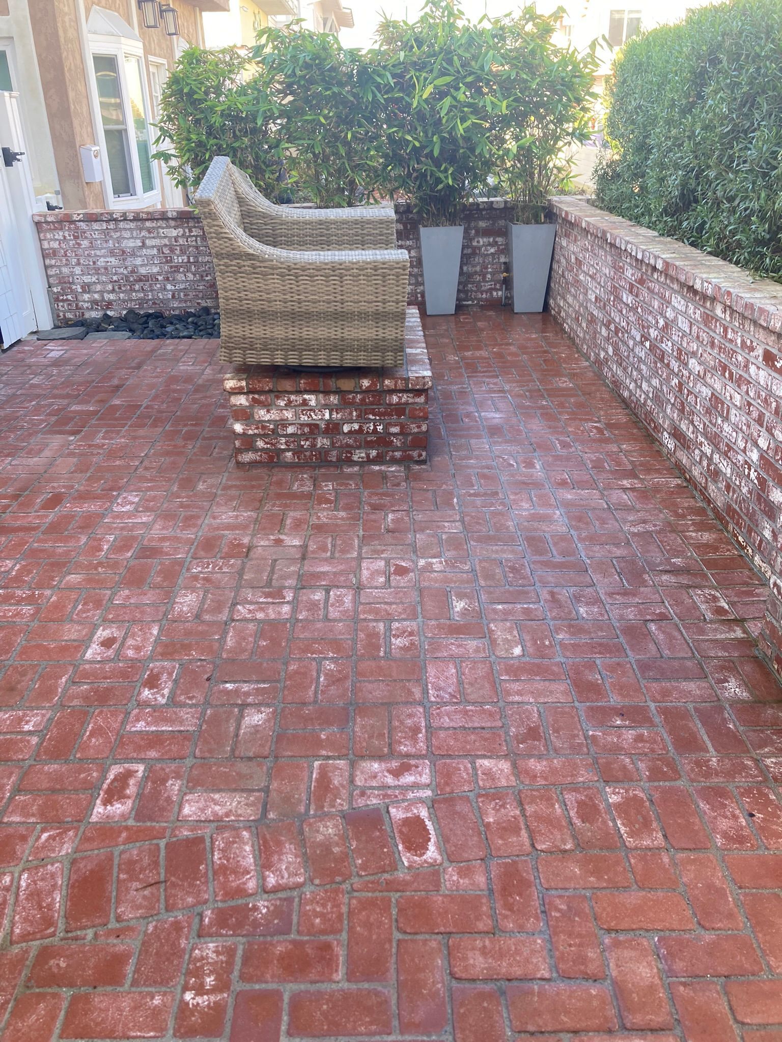 Brick patio with red brick flooring, brick walls, and two outdoor chairs.