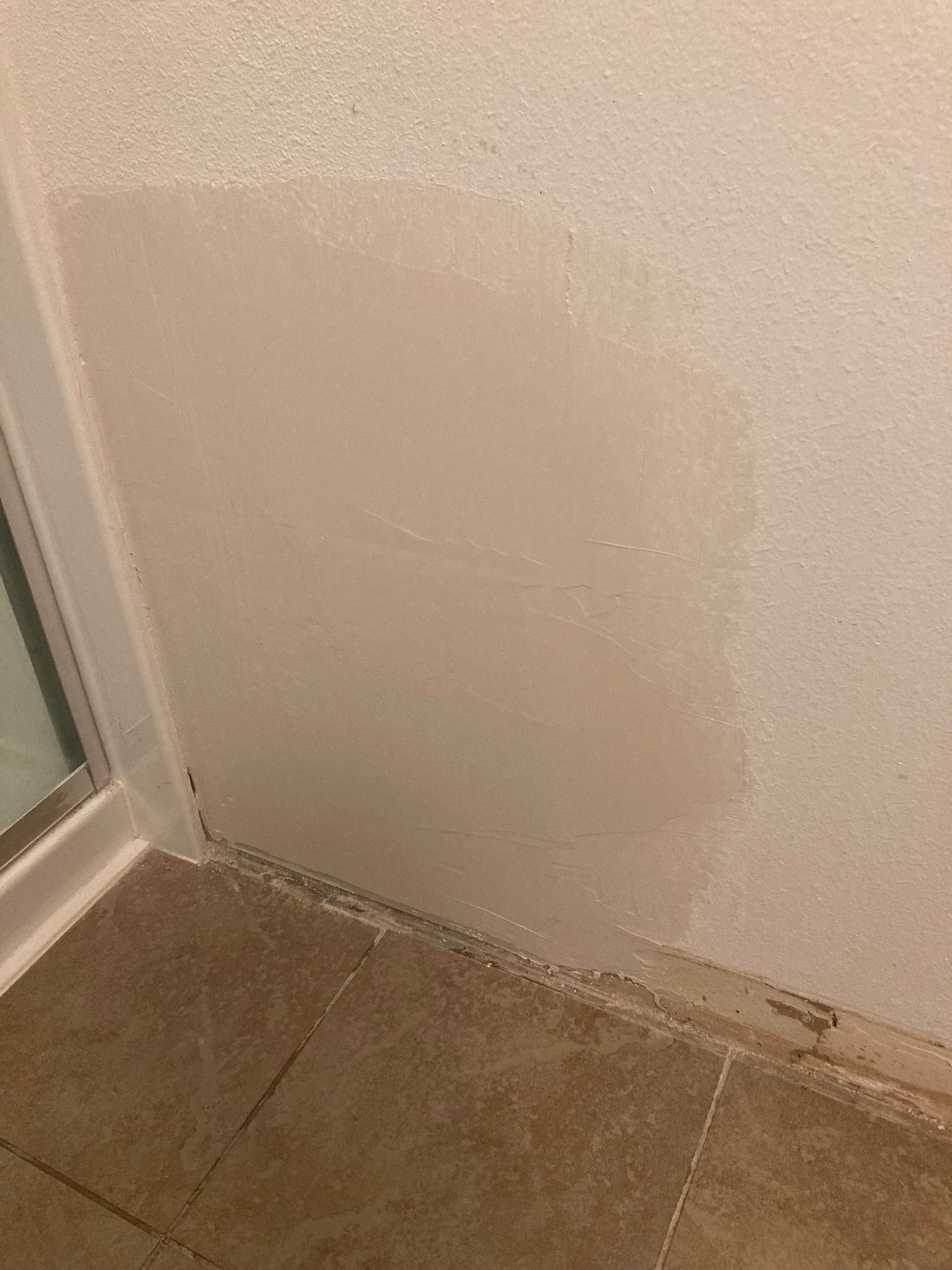 A bathroom with a tiled floor and a white wall.