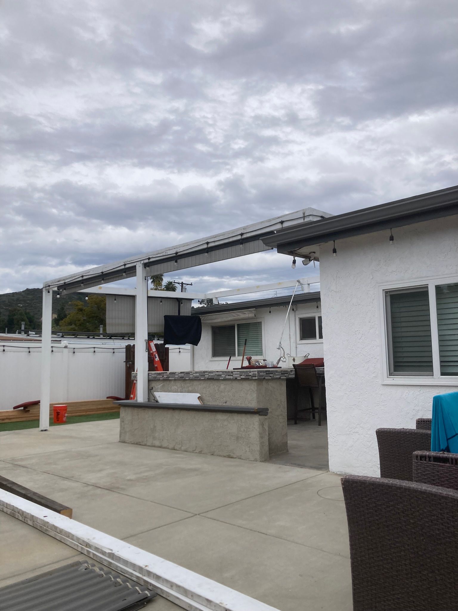 A white house with a patio area and a pergola over it.